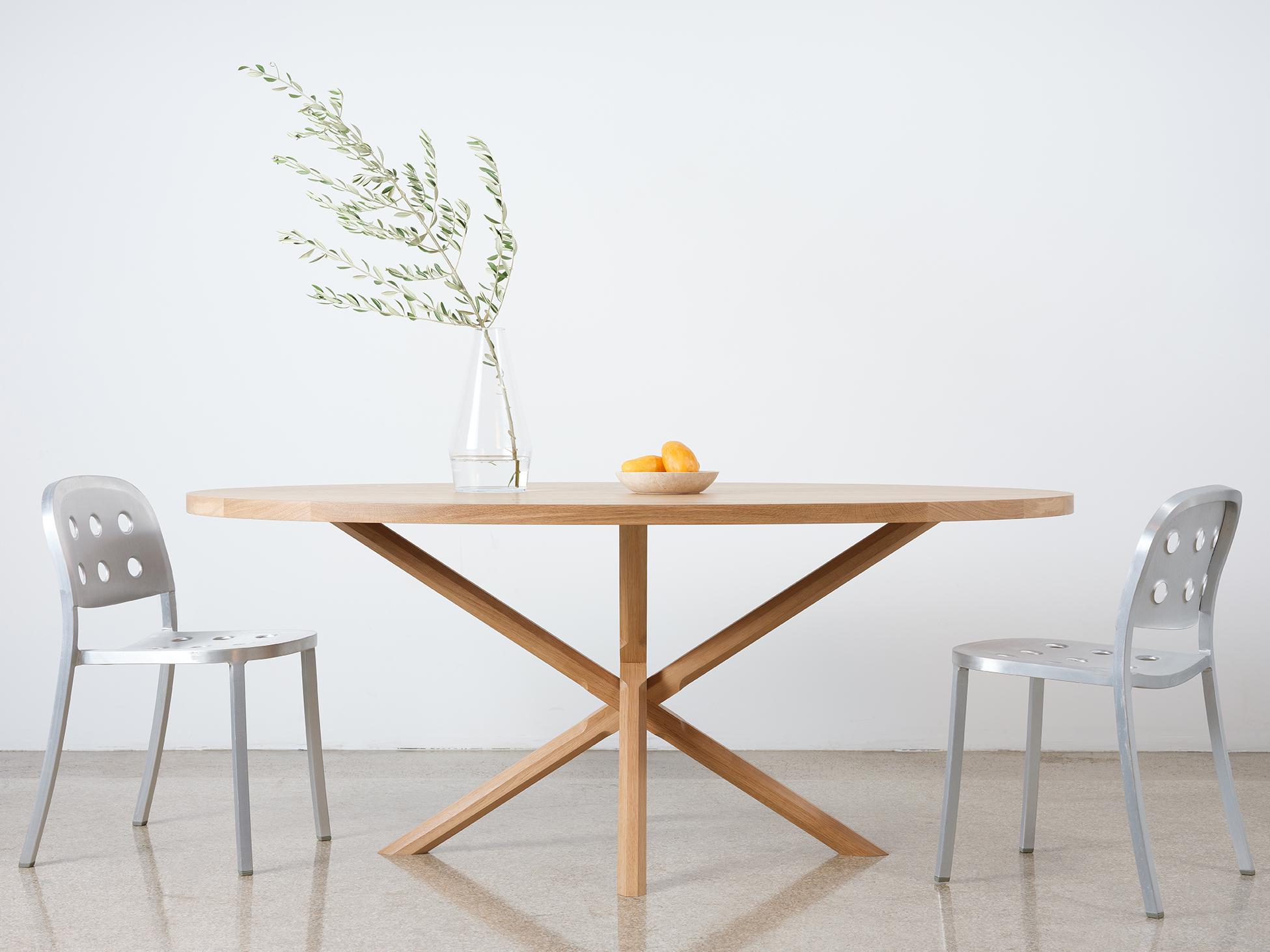 Ce guéridon ovale compact et moderne est construit entièrement en bois dur. Le plateau épais de la table repose sur une base en forme de X avec des pieds polygonaux sculptés de manière complexe. Les pieds sont composés de deux éléments distincts, ce