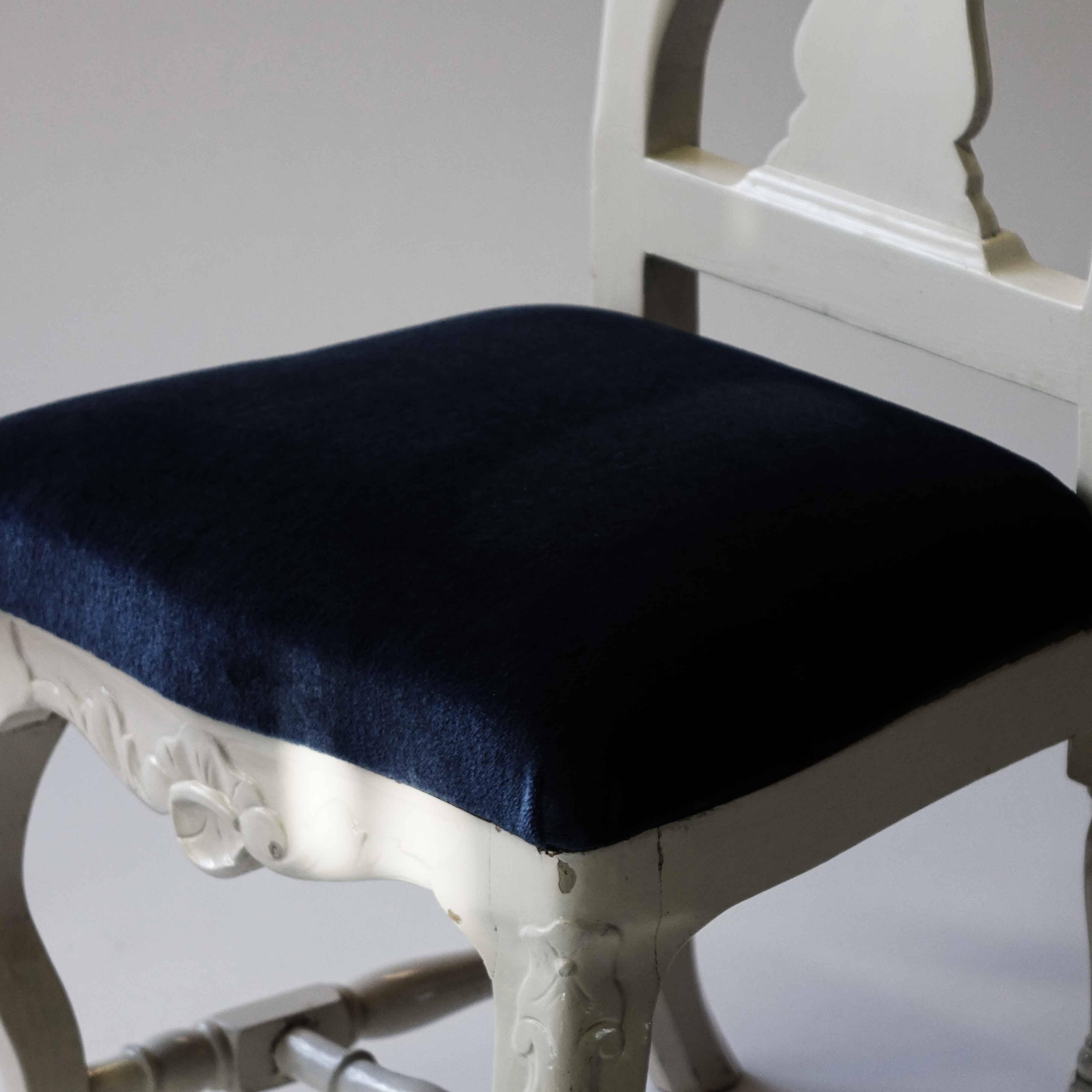 White painted chairs with blue velvet seats in a set of four.