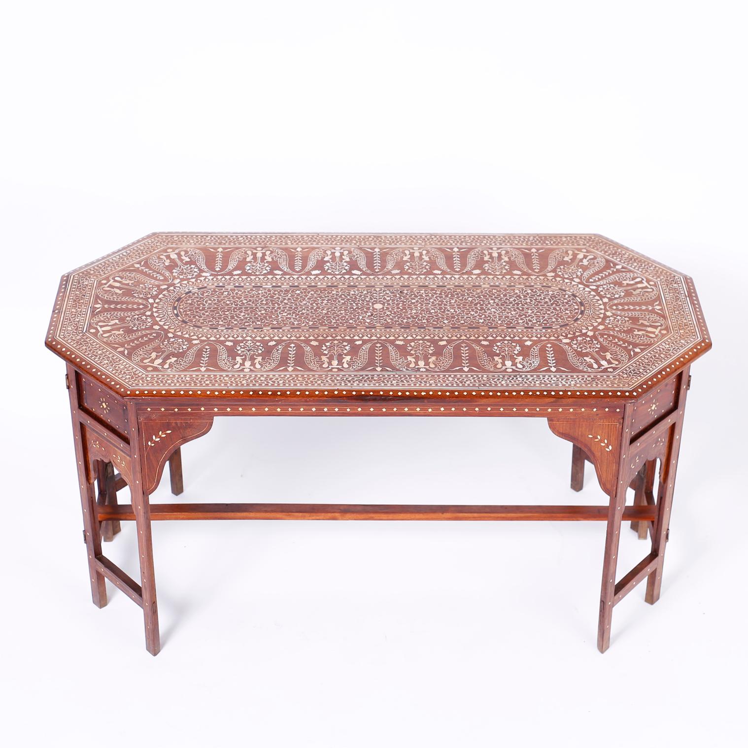 Anglo Indian mahogany coffee table with an elongated octagon form, featuring a top having a center panel with elaborate inlaid floral bone designs emanating from a center button inside repeating graceful tree of life designs. The base has eight legs