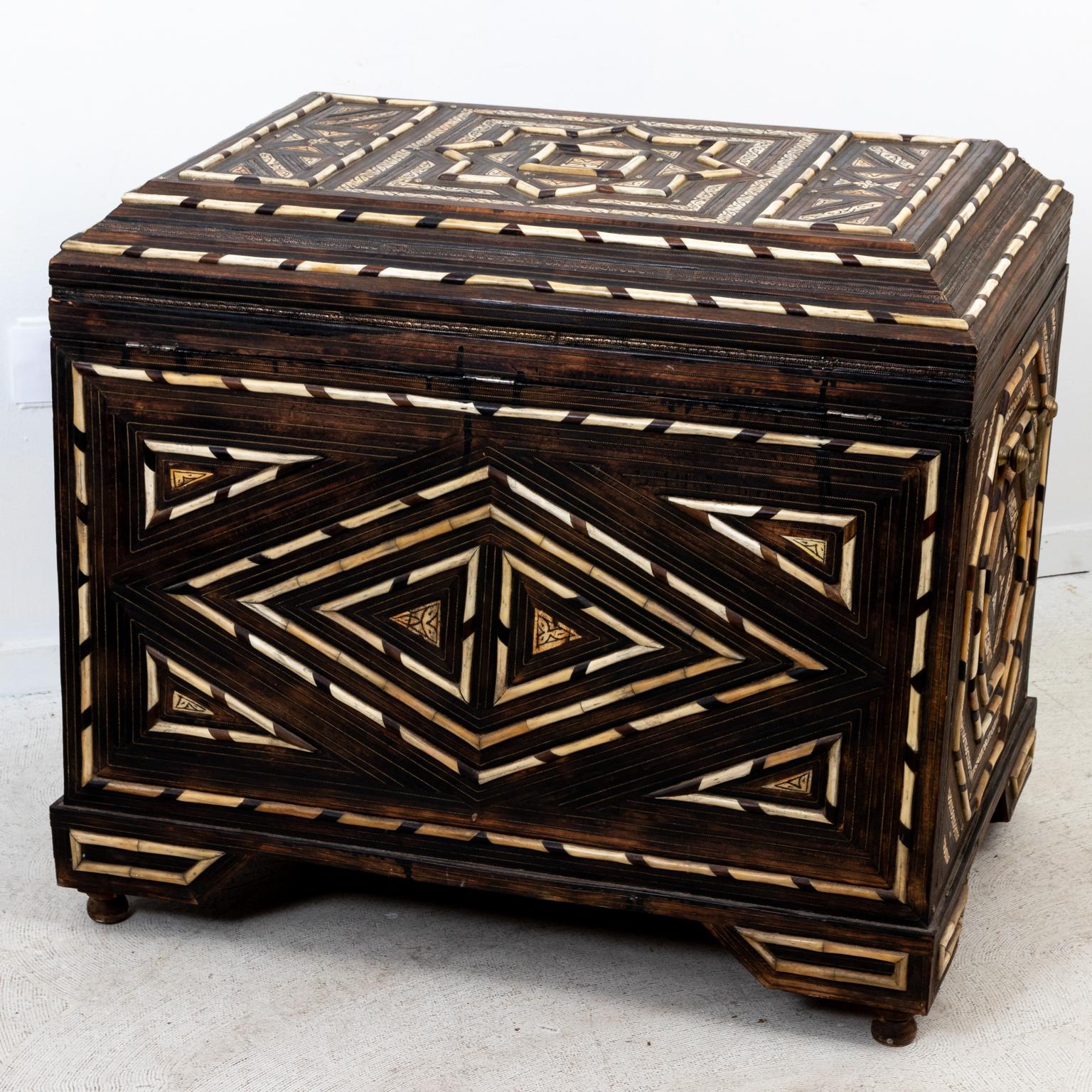 Bone inlaid Anglo-Indian style wooden trunk with metal hardware and geometric designs throughout the exterior of the case such as diamonds,octagons, and a starburst shape on the lid . Further carved detail can be seen on individual inlaid bone