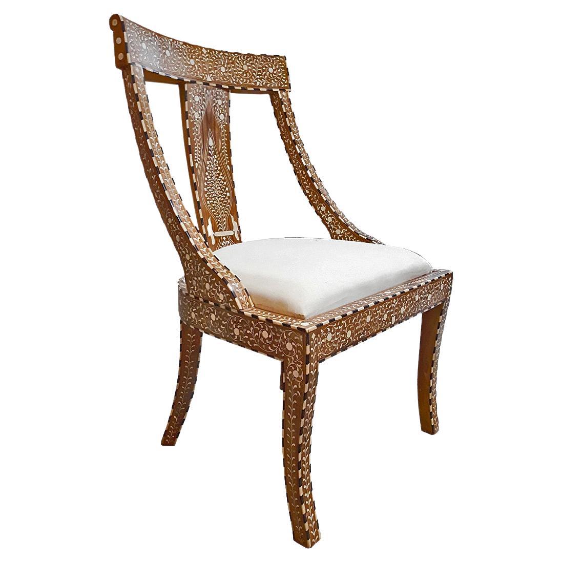 An armless chair from India, hand-crafted by Jaipur artisans in aged teak wood with traditional bone inlays throughout and a removable seat crafted in basic muslin, that can be upholstered to any desired fabric (1 yard COM needed). 

Inlay is