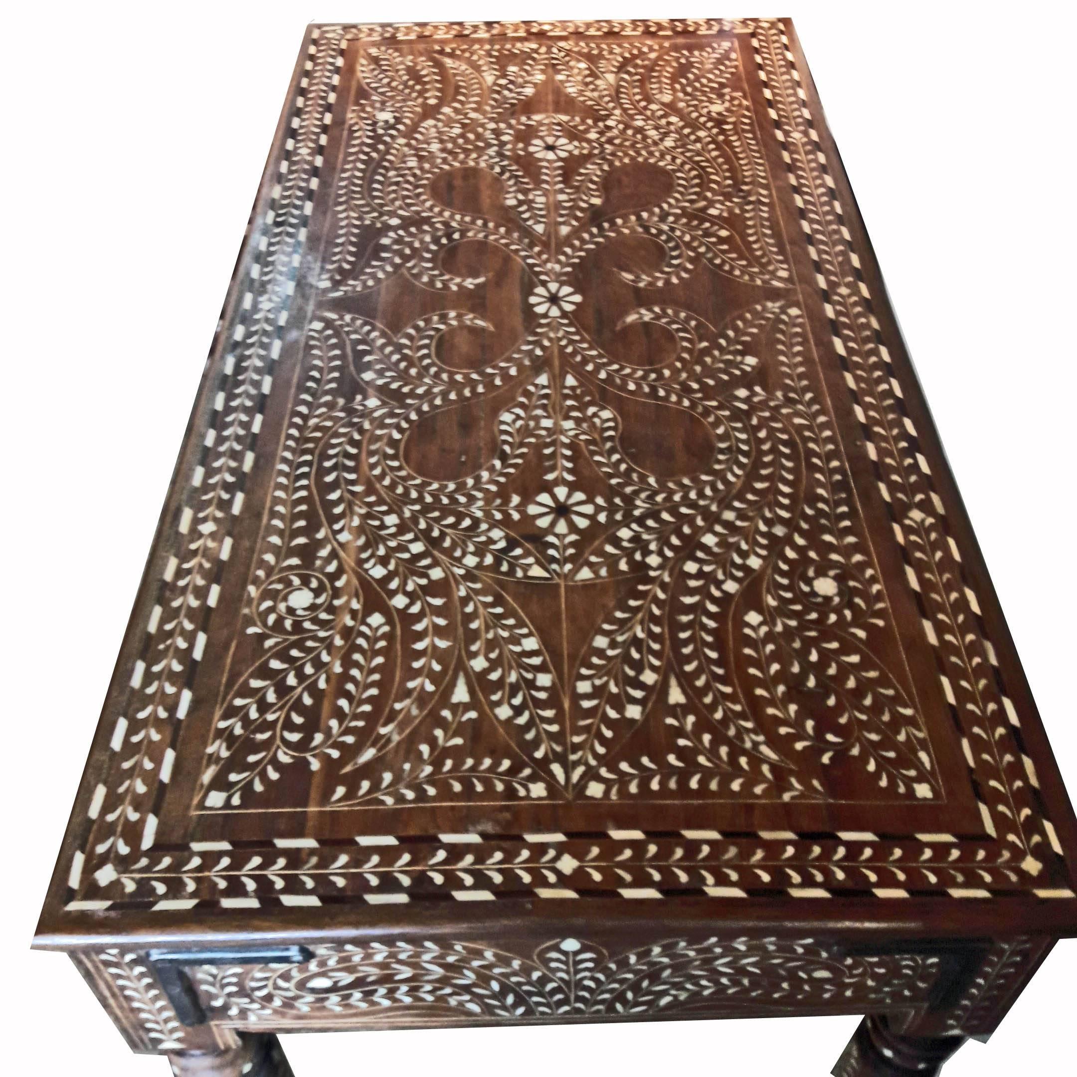A traditional Anglo-Indian desk / table from India. Bone-inlaid teak with an intricate, delicate design. Turned legs. Metal ring pulls, two drawers.
