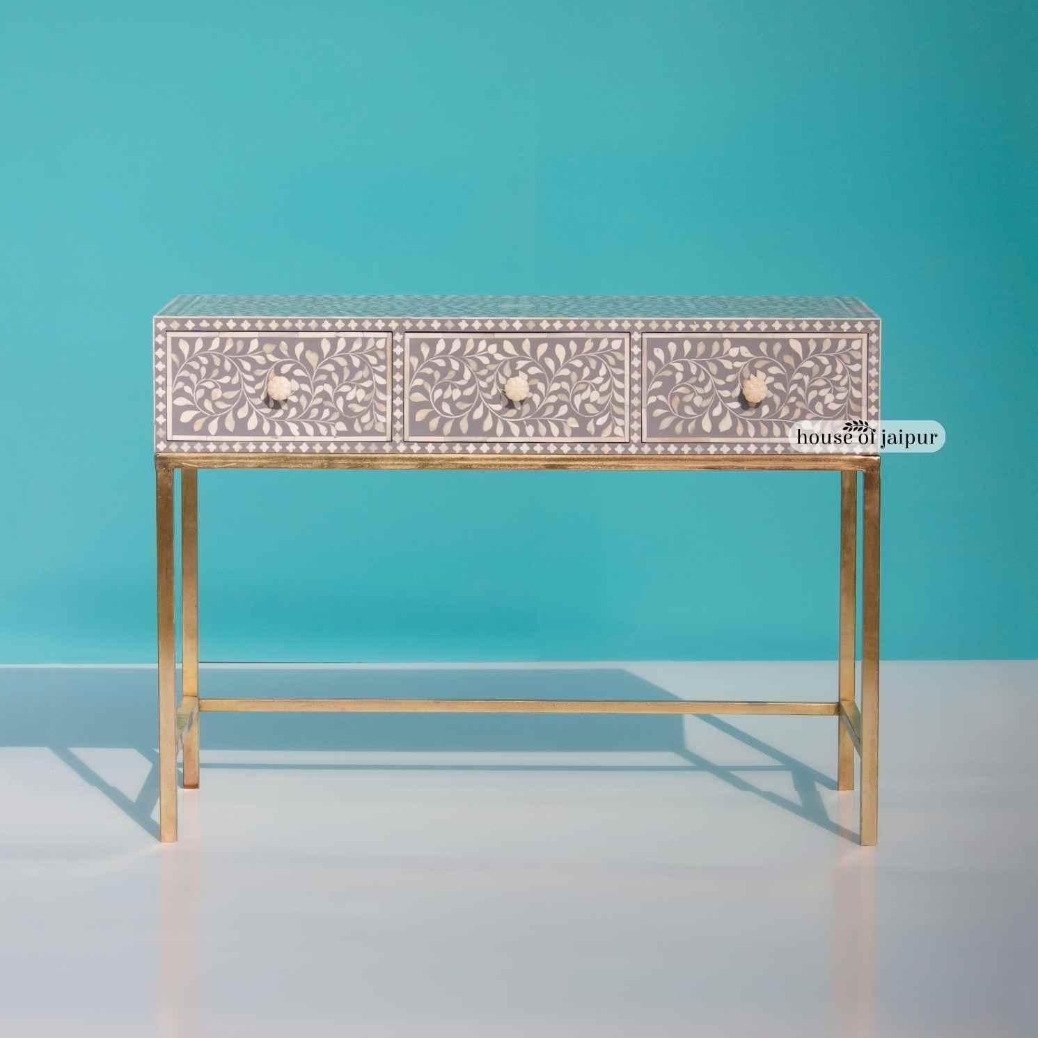 A beautifully handcrafted statement piece, this Bone Inlay Console Table combines traditional artistry with a refined modern silhouette. Featuring an intricate floral vine inlay pattern set against a soft grey base, each bone piece is individually