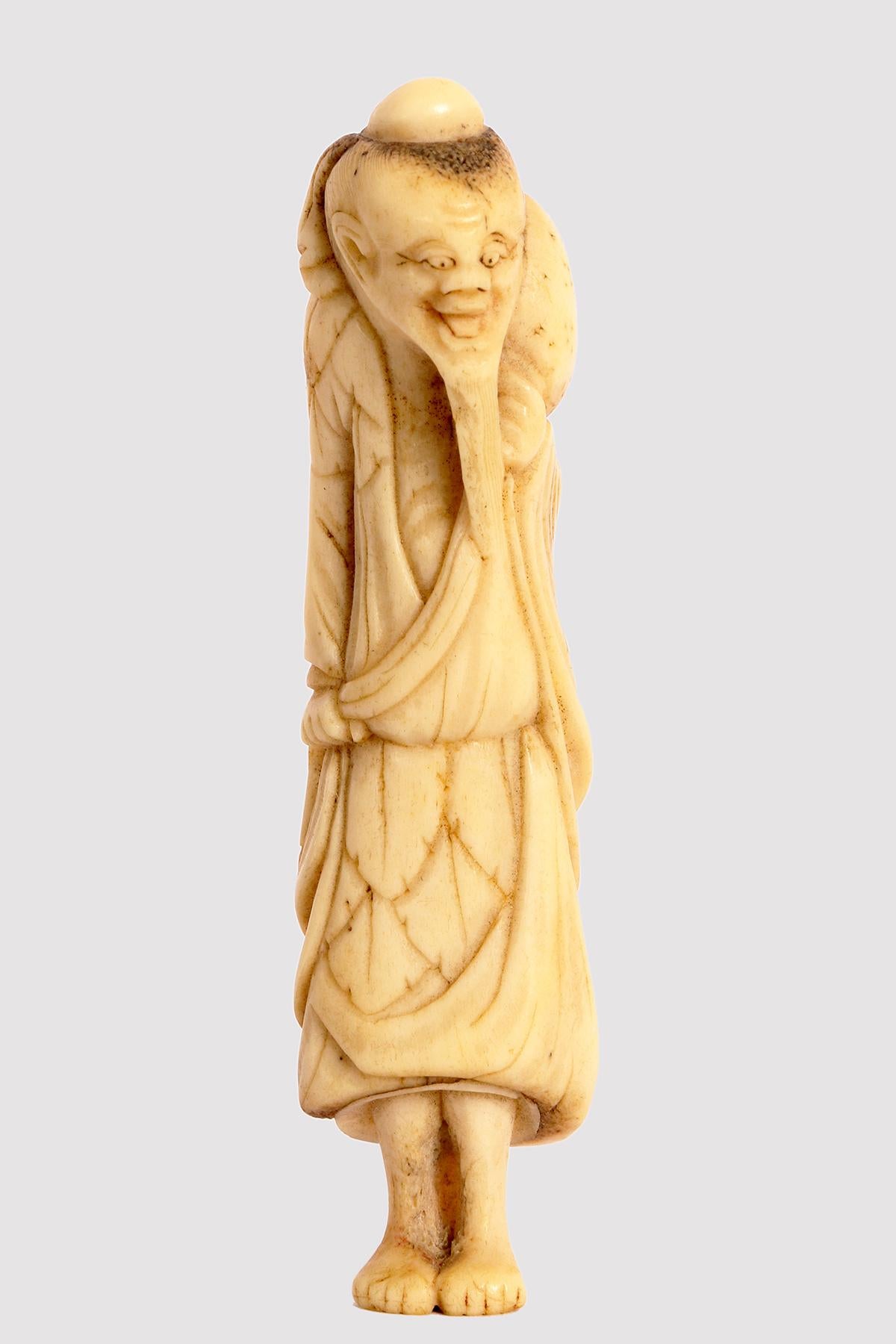 Netzuke aus geschnitztem Knochen, der einen weisen alten Reisenden mit langem Bart darstellt und in ein reiches Gewand gehüllt ist.
Auf der Schulter befindet sich eine getrocknete Kalebasse, um Wasser zu transportieren. Japan, Edo-Zeit (1603-1868),