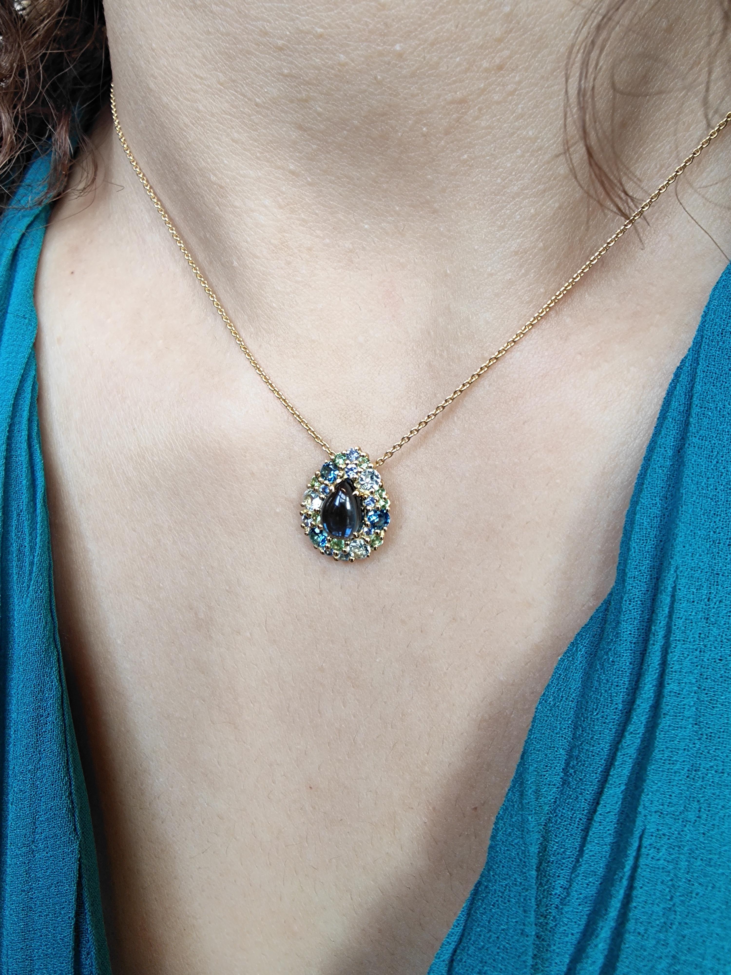 This beautiful, classic pendant is made using solid 18 karat yellow gold and a gorgeous pear shaped cabochon cut London blue topaz. Around are set a mix of tsavorite, iolite, sapphire, a total amount of 2.31 carat of gemstones. The size of the