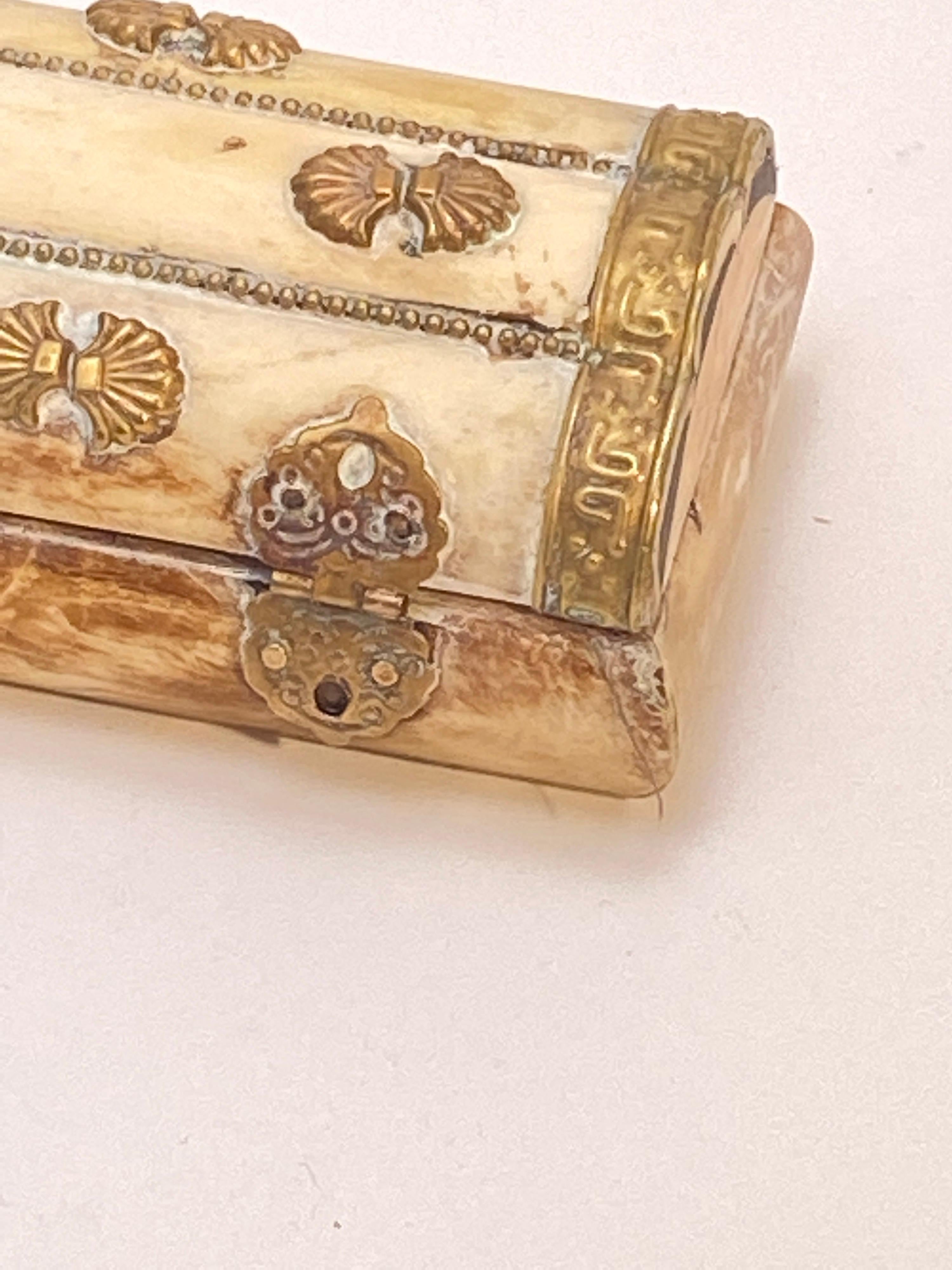 This box is a vintage Indian camel bone jewelry box.
Rectangular shape with hand hammered brass details. Cover has pierced leaf pattern details and brass beads inset in between the bones. Vintage jewelry box lined with felt.
      