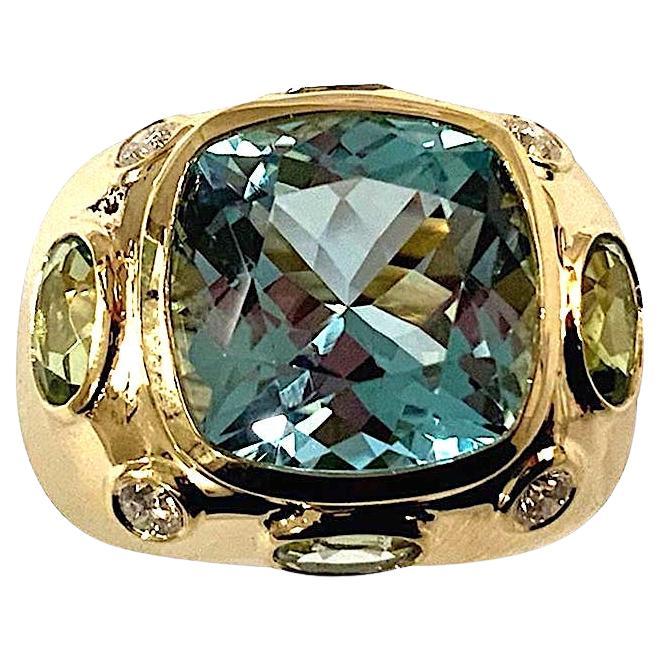 Anello BONHEUR su misura di Christina Addison: anello a cupola in oro giallo 18 carati con pietra centrale sfaccettata con taglio a cuscino in Topazio Azzurro, due Peridot ovali sfaccettati, due Topazio Azzurro ovali sfaccettati e diamanti rotondi.