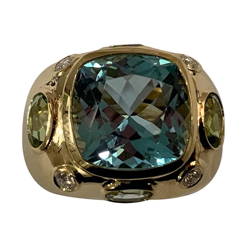 The BONHEUR Ring: 18kt Yellow Gold Domed Ring with faceted Light Blue Topaz Cushion cut center stone and two faceted oval Peridot and two faceted oval Pale Blue Topaz and round Diamonds. 

This ring is available in in any color stone combination. 