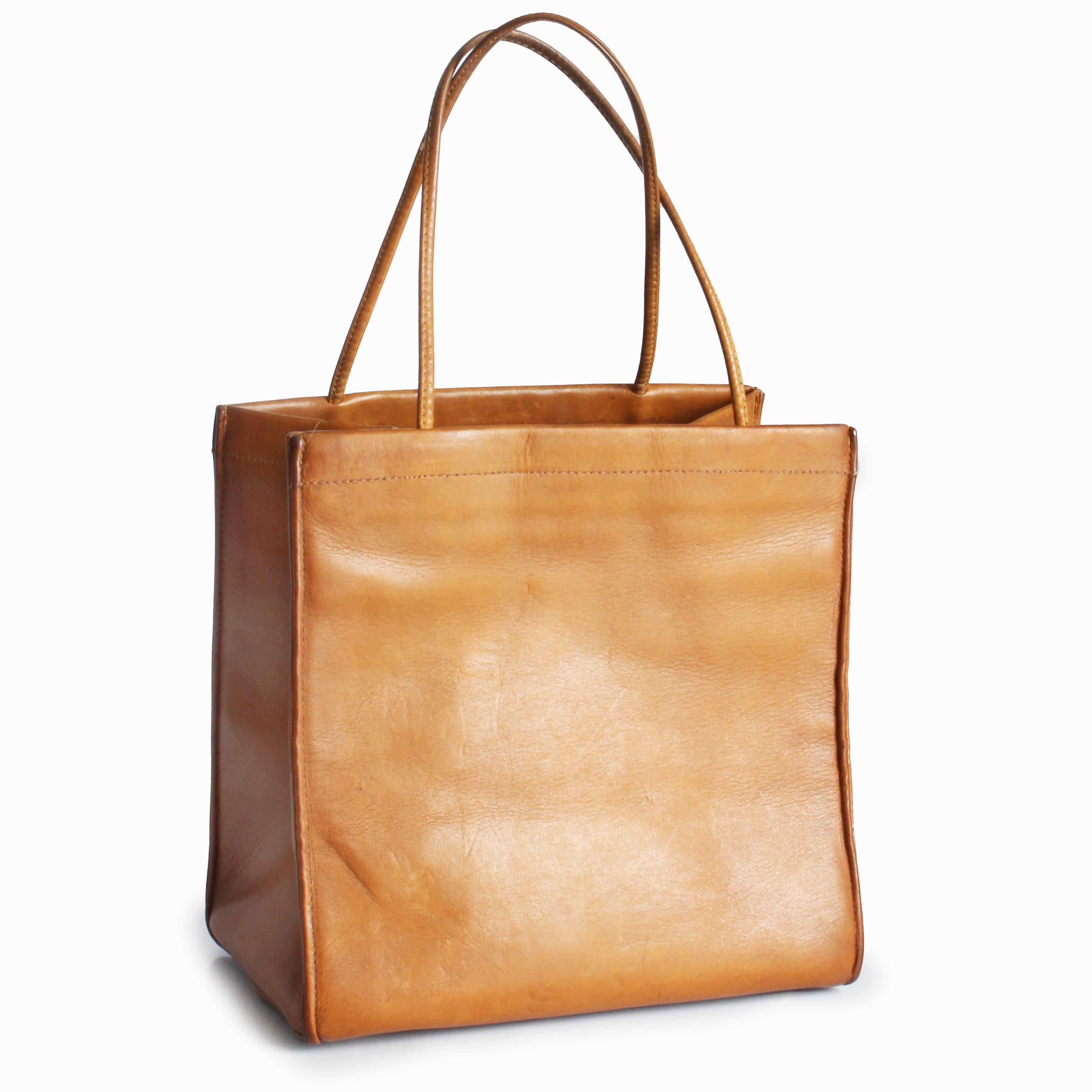 Preowned, vintage Bonnie Cashin for Coach 'lunch bag' tote, likely made in the 1960s.  Made from a smooth tan harness leather, it's shaped like a paper bag and designed to fold flat for storage! The interior is lined in Cashin's signature striped