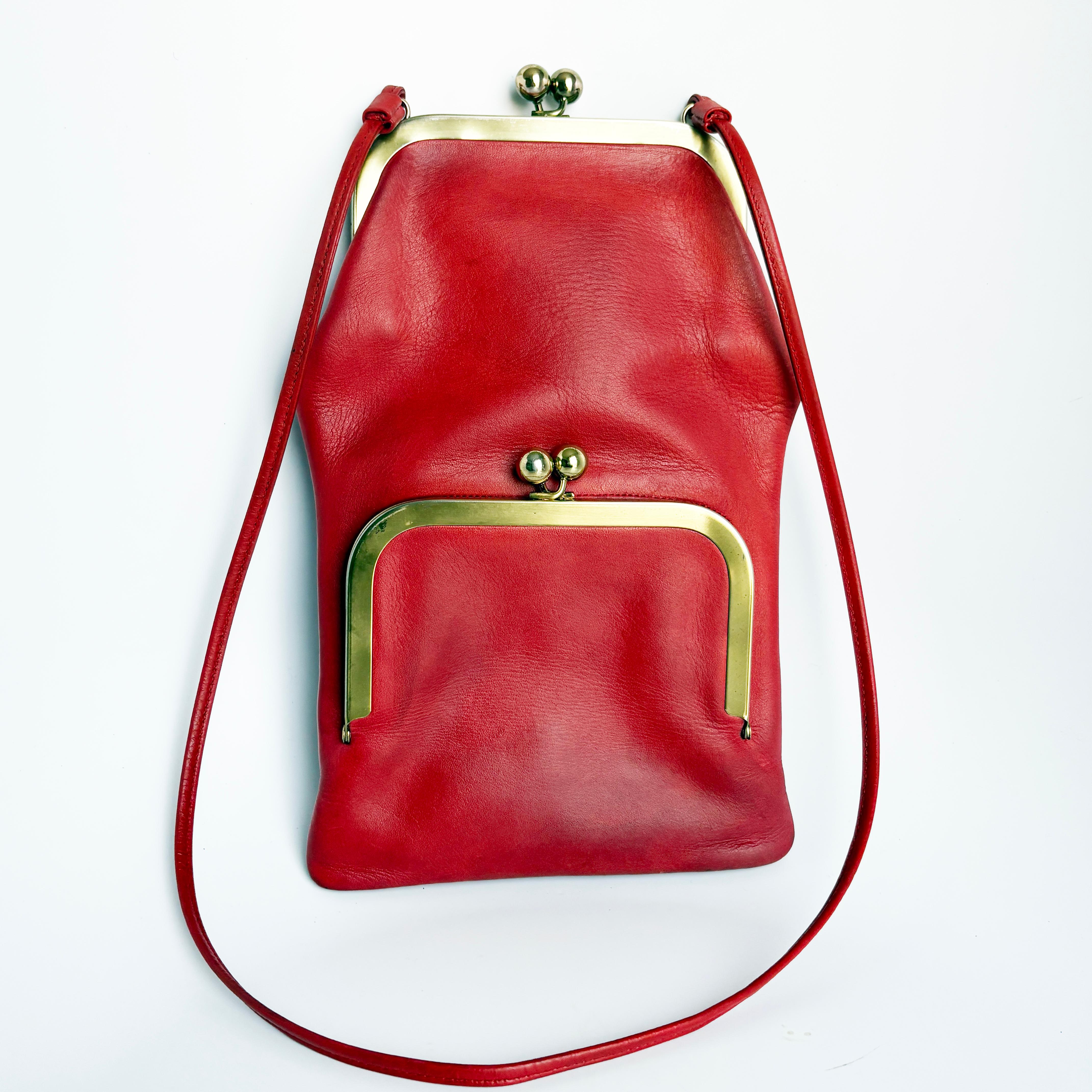 Gebrauchte, alte Bonnie Cashin for Coach Swinger Tasche, wahrscheinlich aus den 70er Jahren. Sie ist aus patiniertem, leuchtend rotem Leder gefertigt und verfügt über doppelwandige Taschen mit Kussmundverschluss aus Goldmetall und einen schmalen