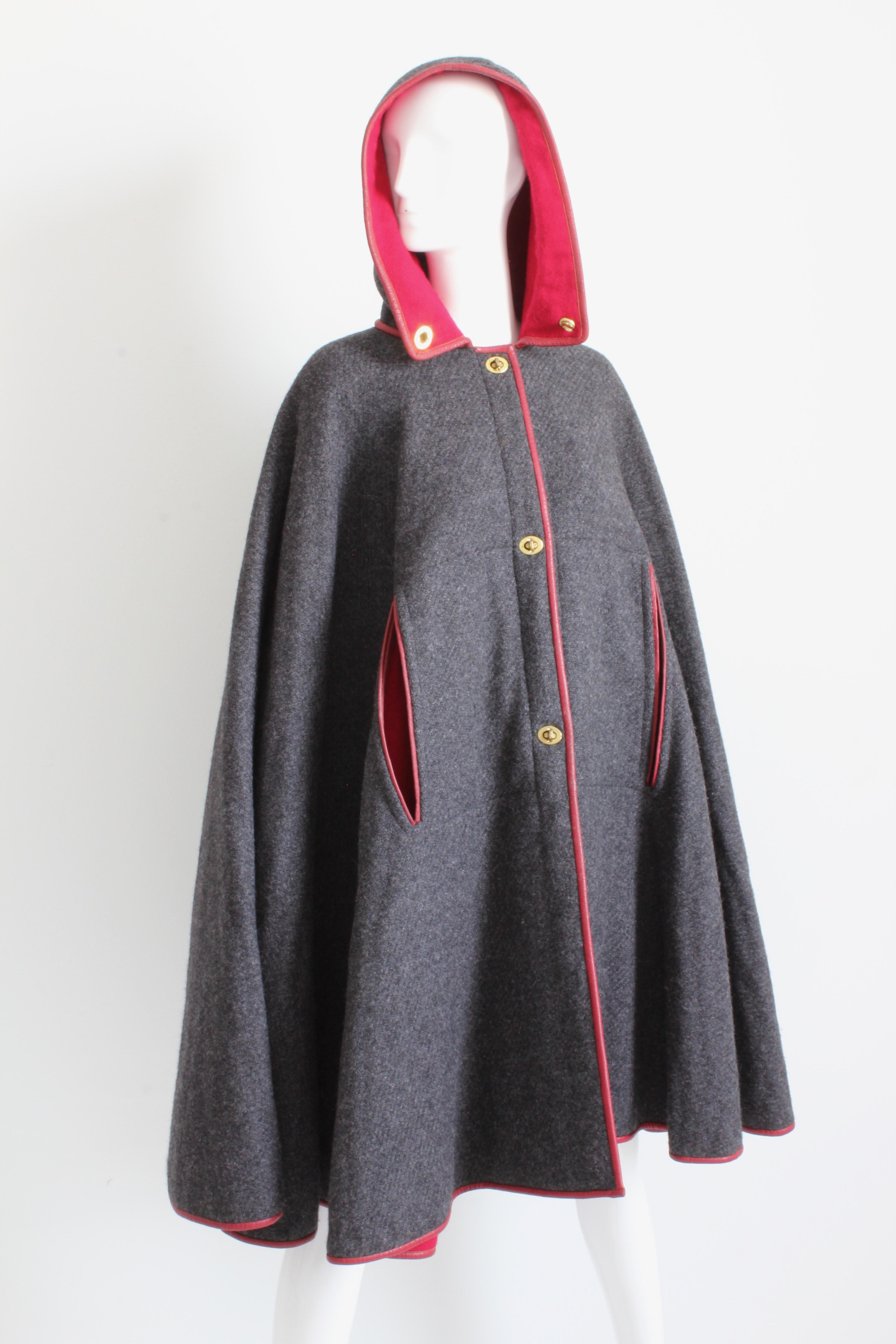 This fabulous hooded cape was designed by the mother of American sportswear, Bonnie Cashin, during her time at Sills. 

Made from a rich charcoal gray wool, this piece is fully lined in a vibrant cherry red wool jersey and features matching red