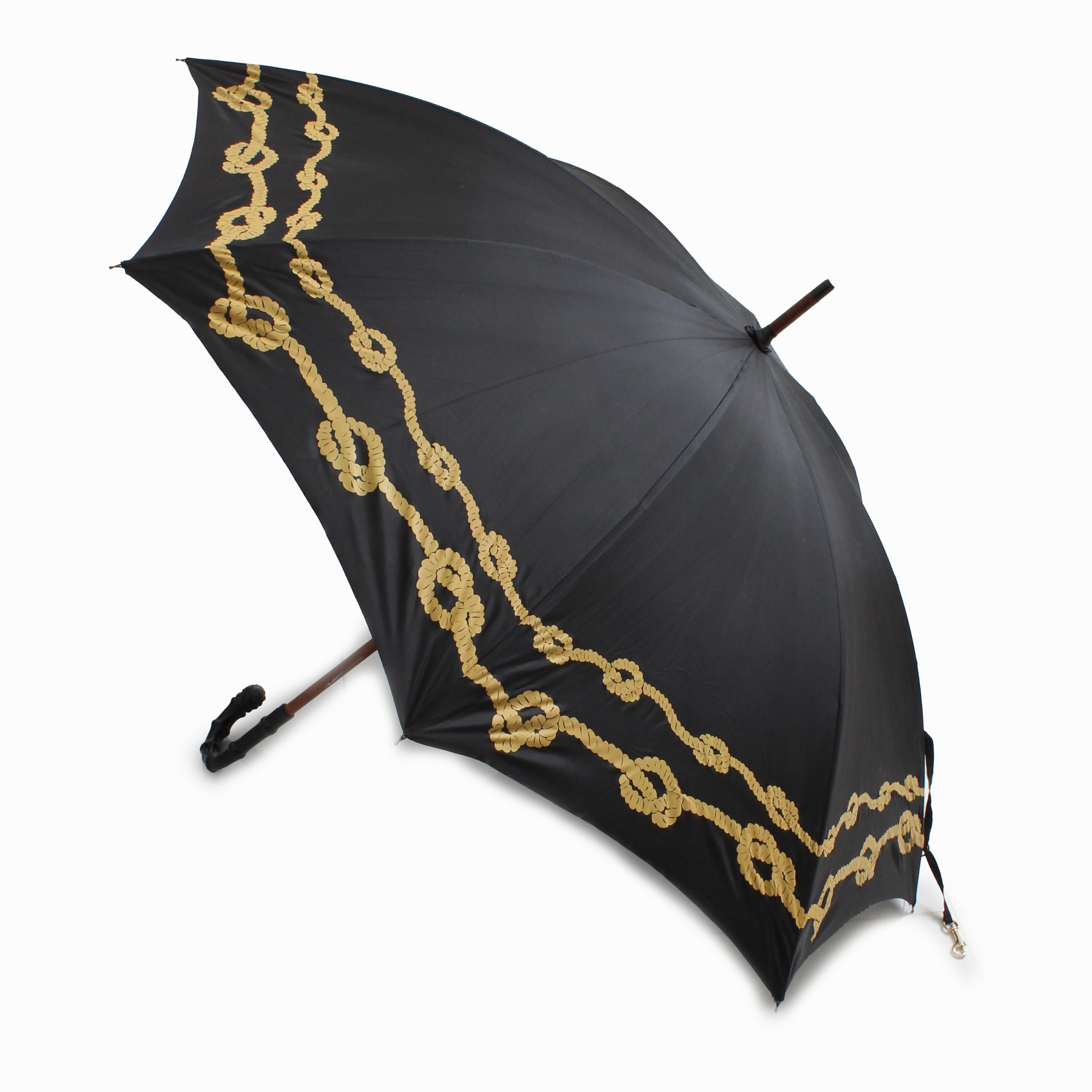 Preowned, vintage Bonnie Cashin for D. Klein New York large umbrella, likely made in the 70s.  Made from black nylon fabric with a knotted gold rope motif, it features an ornate carved black handle, a wooden shaft and a brass dog-leash cinch strap!