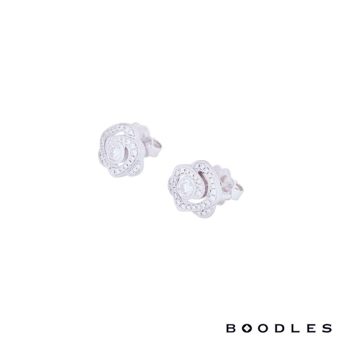 An elegant pair of platinum earrings from the Maymay Rose collection by Boodles. Each earring has a single round brilliant cut diamond in the centre, surrounded by pave set diamonds in the form of petals. There are 68 diamonds in total with an