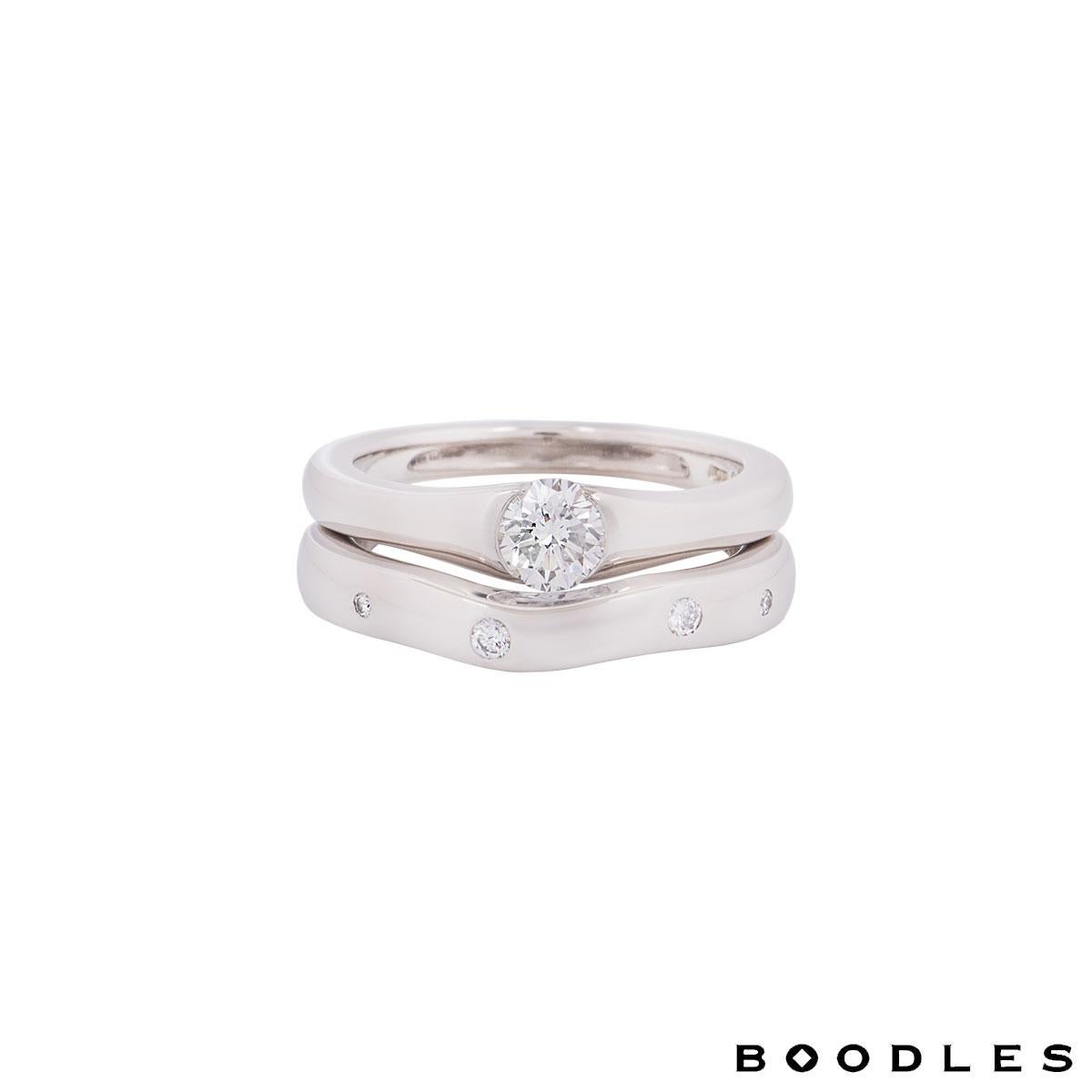 A stunning platinum diamond bridal set rings by Boodles. The ring features a round brilliant cut diamond in a tension setting with a weight 0.49ct along with a scattered diamonds matching wedding band designed to accompany the ring with an