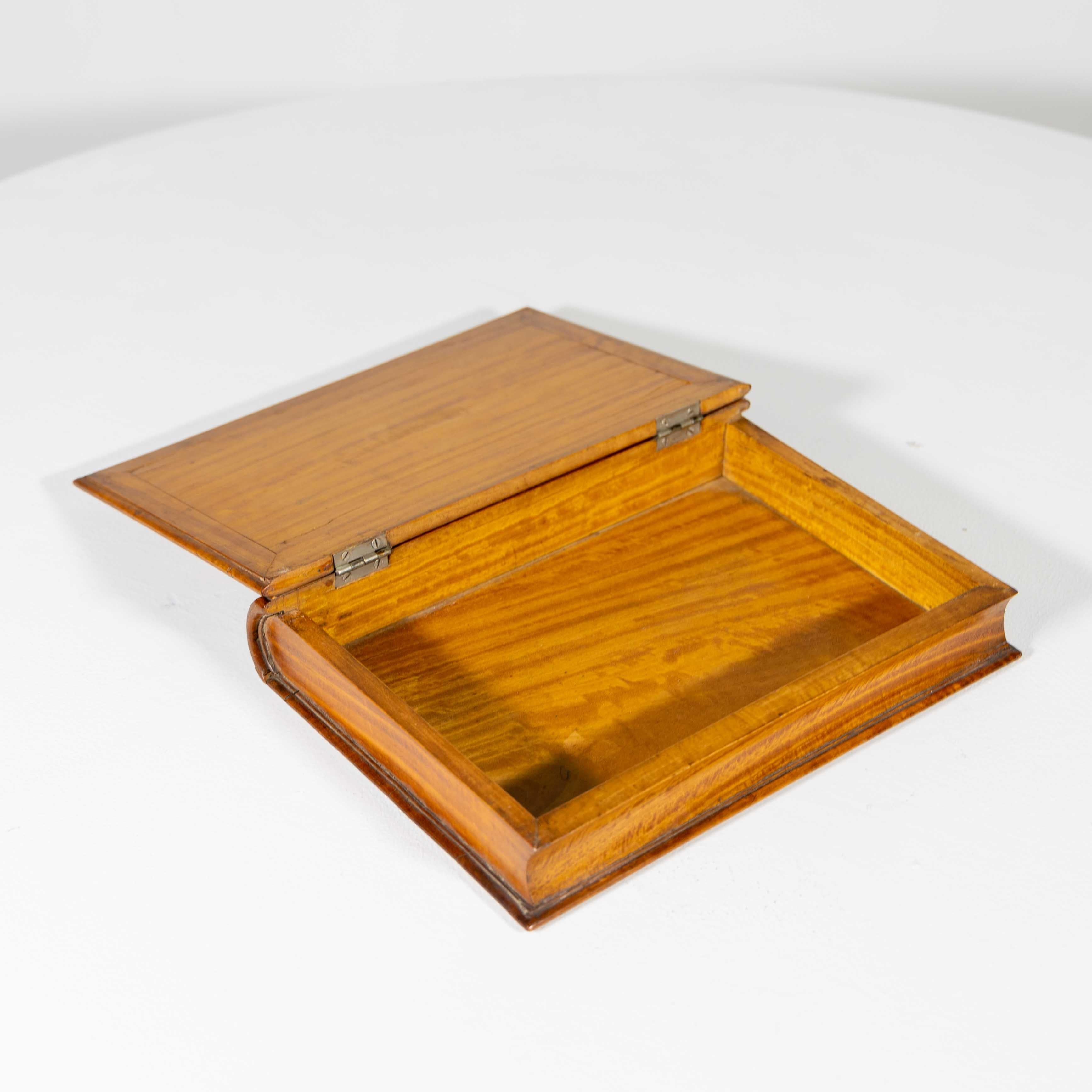 Dekorative, englische Schmuckschatulle aus Zitronenholz in Form eines Buches mit angedeuteten Buchrippen und Fadenintarsien auf dem Scharnierdeckel.
