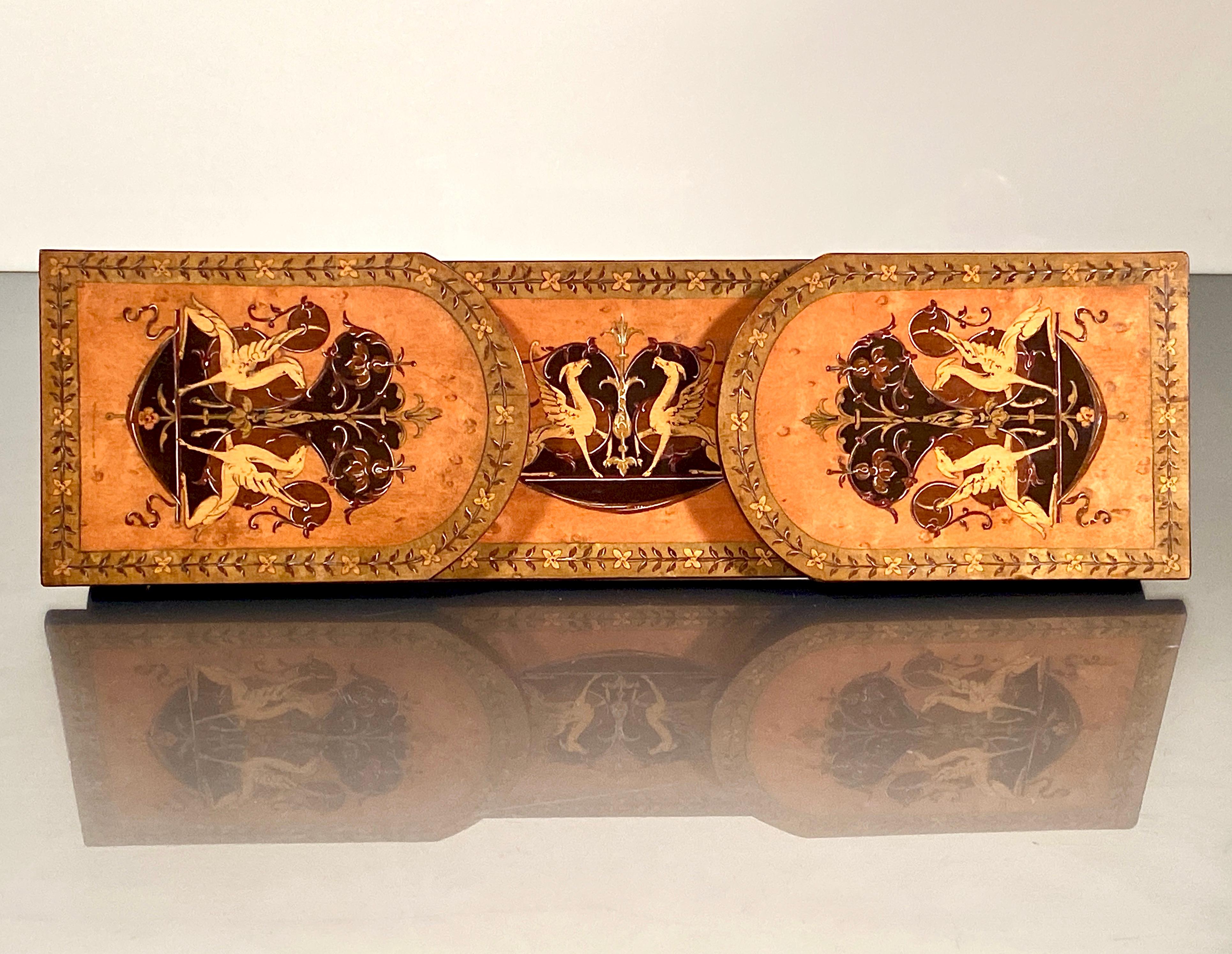 Inlaid book slide extending bookend rack.
A late 19 century continental marquetry book slide featuring a design on 3 sides of winged griffins amongst floral sprays inlaid with coloured sycamore and maple.

Two hinged leaves on an extending plank