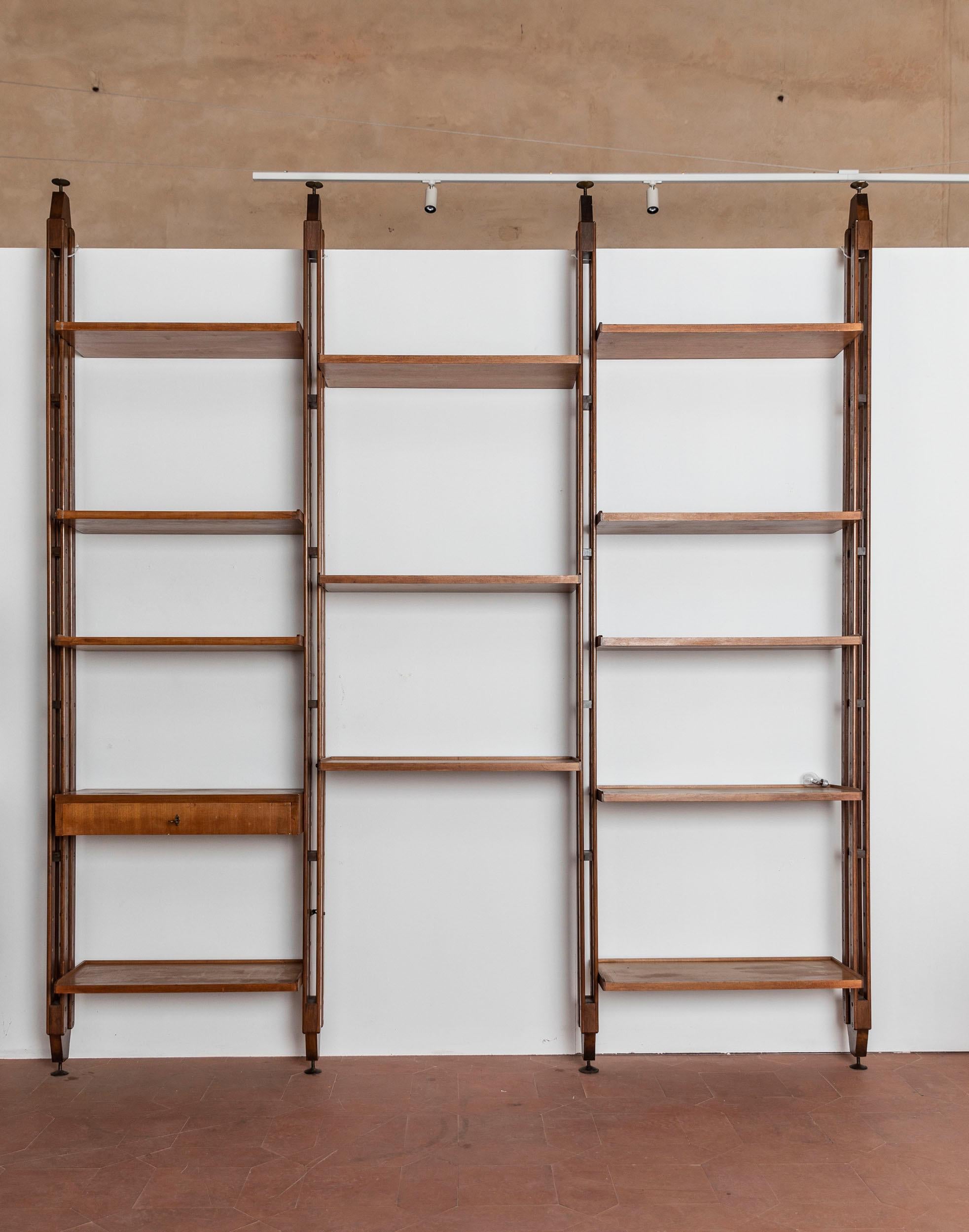 Large mid-century bookcase attributed to Paolo Tilche from the 1960s. Black steel clamps are screwed to the floor and ceiling, into which the shelf stands are inserted. A very simple system that offers high stability, even if the shelf is to be in
