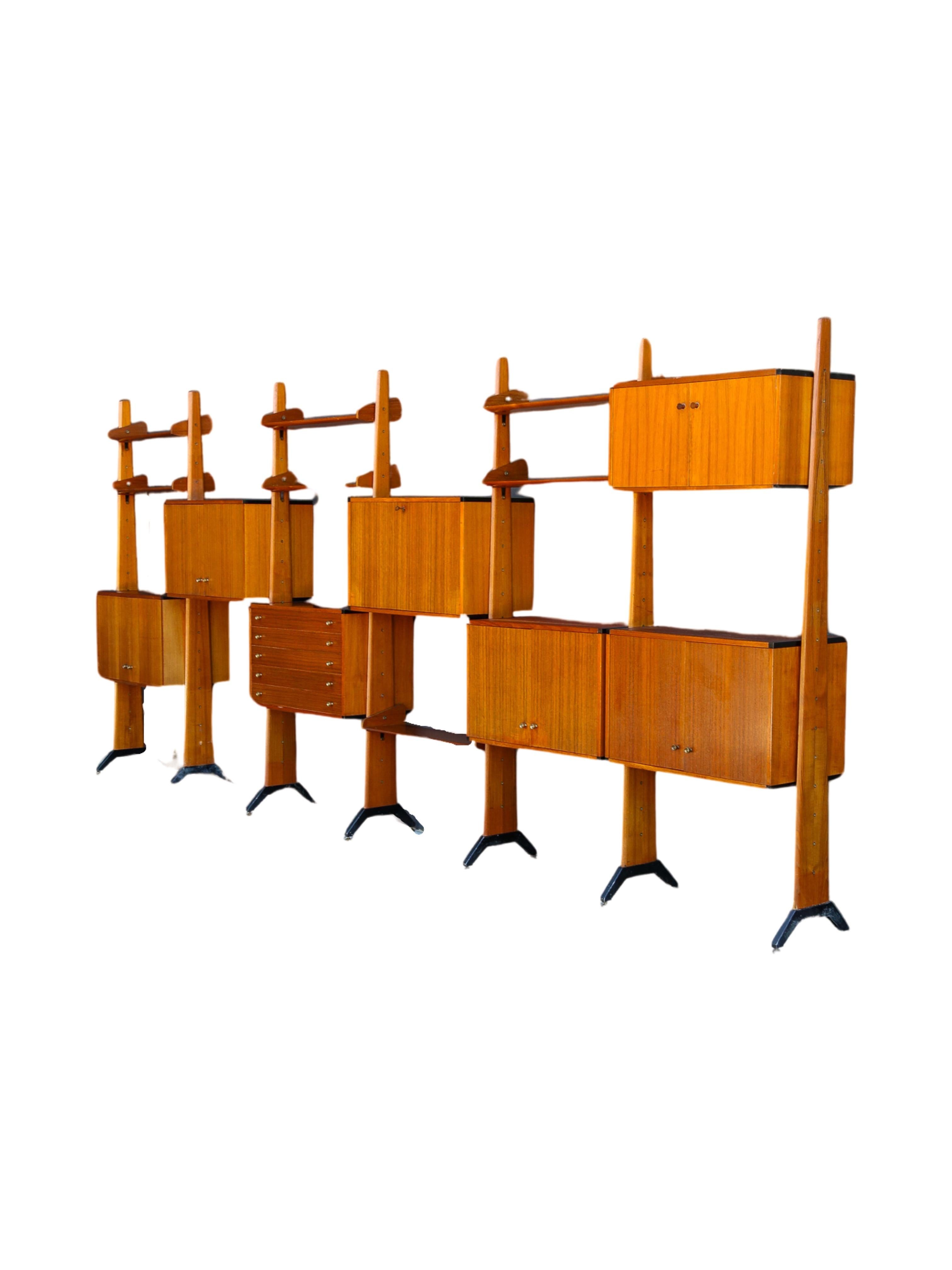 Italian Mid Century Modern bookcase by AV Arredamenti Contemporanei 1960s. The structure is made of solid and veneered teak wood with adjustable brass feet. It has one drawers module, nine cabinet modules and seven shelves that you can place as you