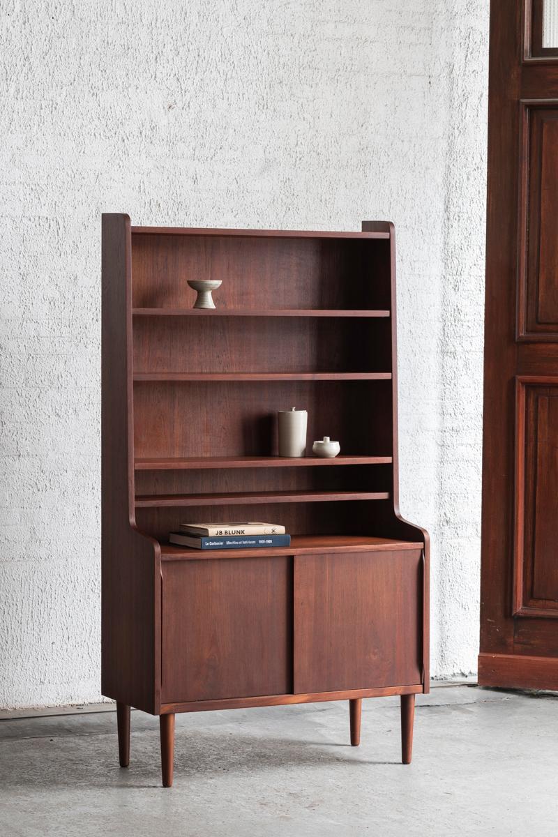 Bookcase designed by Erik Petersen and produced by EP Mobler in Denmark around 1960. Solid teak and teak veneer. The bookshelf has a cabinet underneath and adjustable shelfs above. In good condition with some small wear as shown in the pictures.

H:
