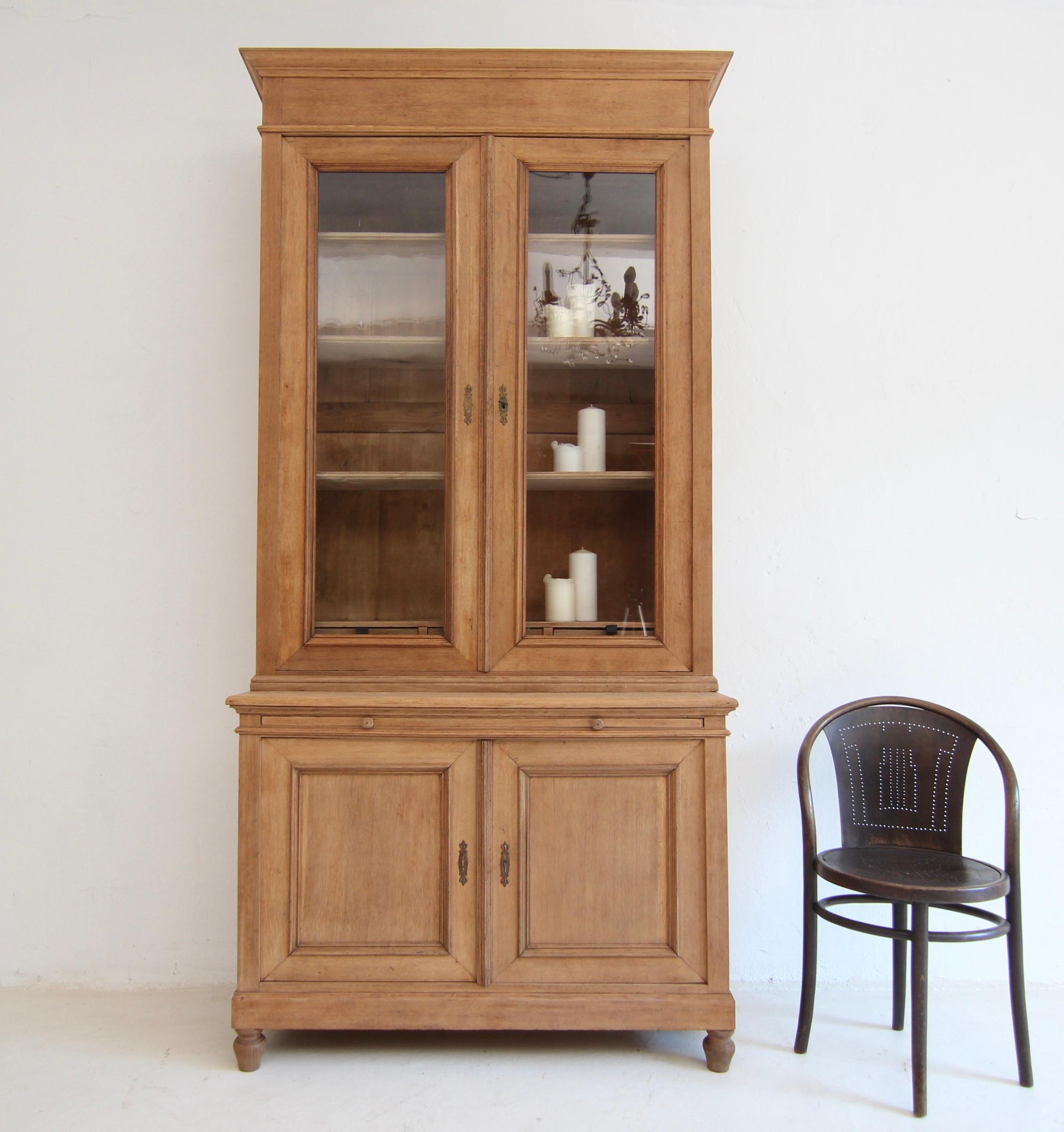 Tall bookcase from around 1900. Very beautiful classic design, made of solid oak wood. 

Two-part oak body in frame construction, consisting of base cabinet and display cabinet top, each with a lockable double door. The base cabinet has a pull-out