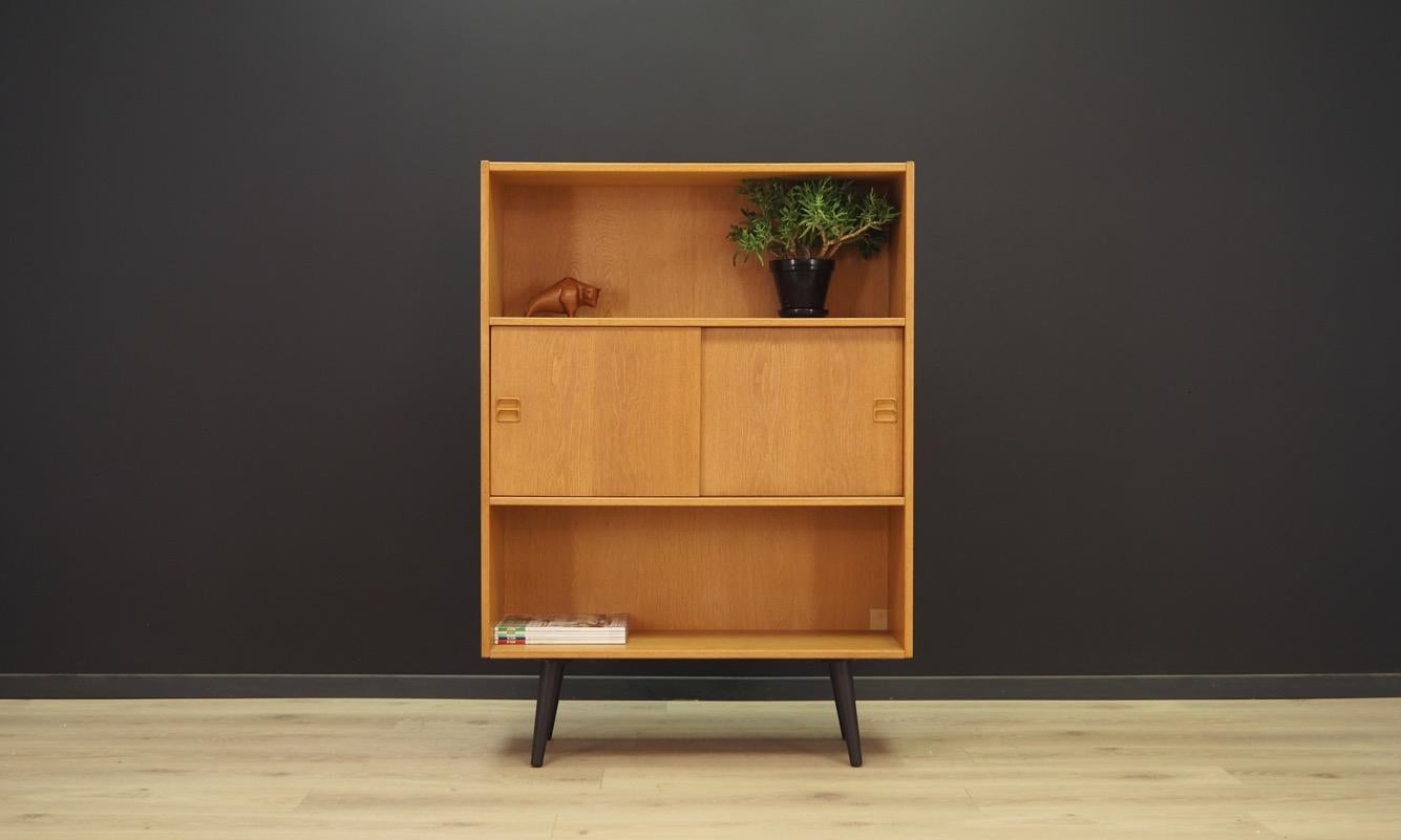 A brilliant bookcase - library from the 1960s-1970s. Danish design - minimalistic form, attention to details. The surface of the furniture covered with ash veneer. Two shelves behind a sliding door. Preserved in good condition (minor bruises and