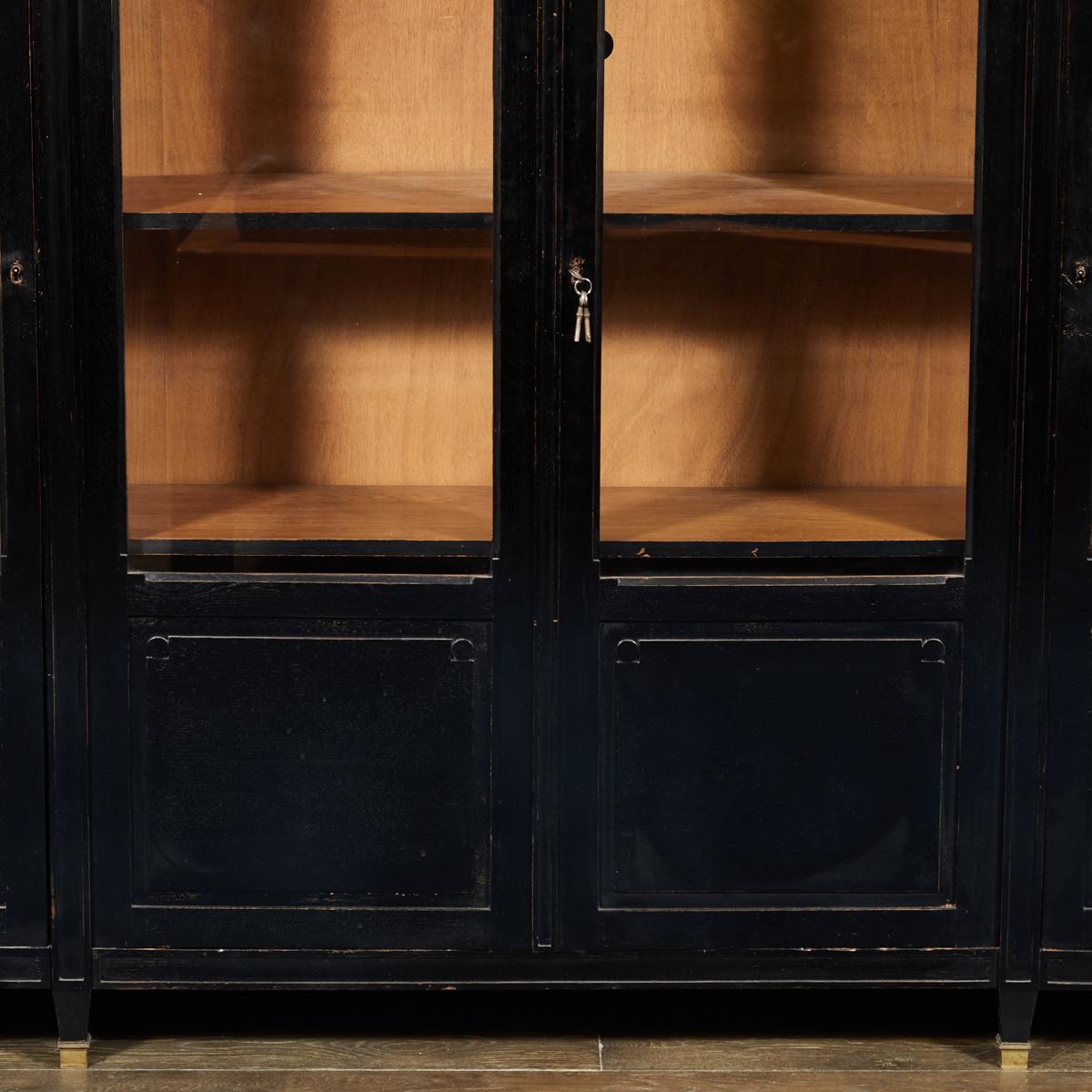 This is an ebonized black oak bookcase with original brass capped hinges dating to the late 19th Century. Key is present. The interior of the bookcase is unpainted and left as the natural oak. This piece would be great as statement storage for a