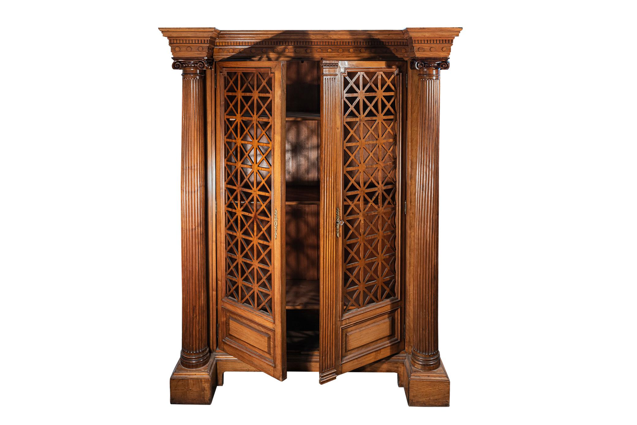 Bookcase in the style of Kerylos, 
Neoclassical lattice doors in the shape of the antique,
Corinthians capitals columns,
Wood,
France, circa 1930.

Measures: Width 131 cm, depth 60 cm, height 170 cm.