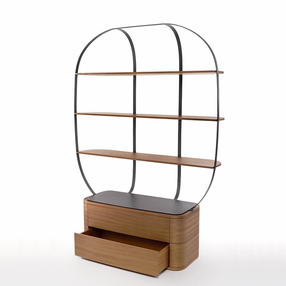 Here the bookcase Klec in the large version in mahogany, a tropical wood with red tints to warmup your interior. A bookcase with rounded shapes playing with the contrast of wood and metal, of its lightweight, near-levitating shelves in an open cage