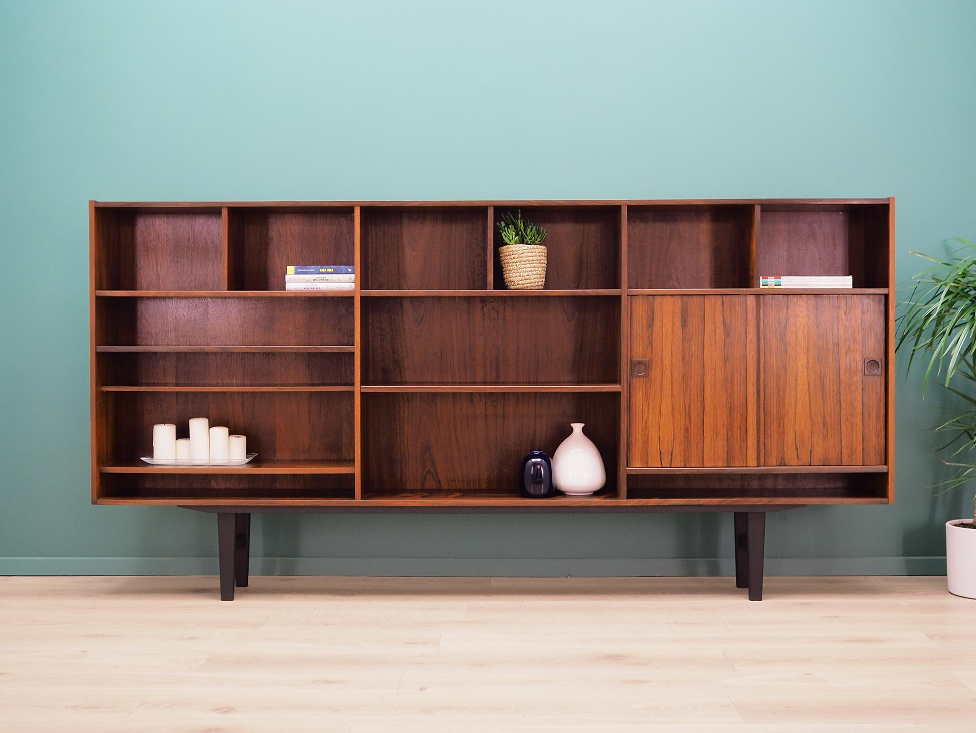 Bookcase was made in the 1960s by the well-known Danish furniture producer Farsø Møbelfabrik.

The structure is covered with rosewood veneer. Legs made of solid wood are black coloured. Surface after refreshing. Inside the space has been filled