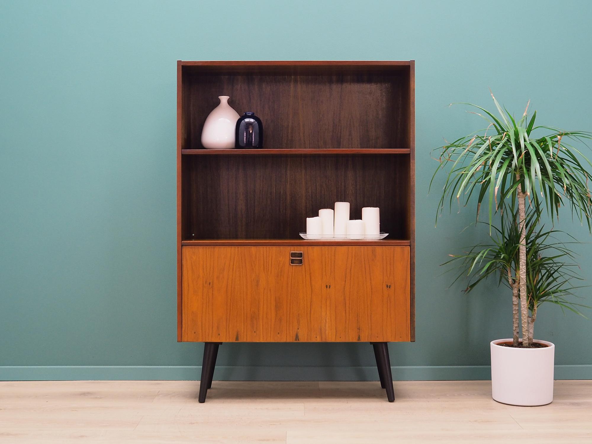 Bookcase was made in the 1960s-1970s, Danish production.

The structure is covered with rosewood veneer. Legs made of solid wood stained black. Surface after refreshing. Inside the space was filled with a practical shelf with adjustable height.