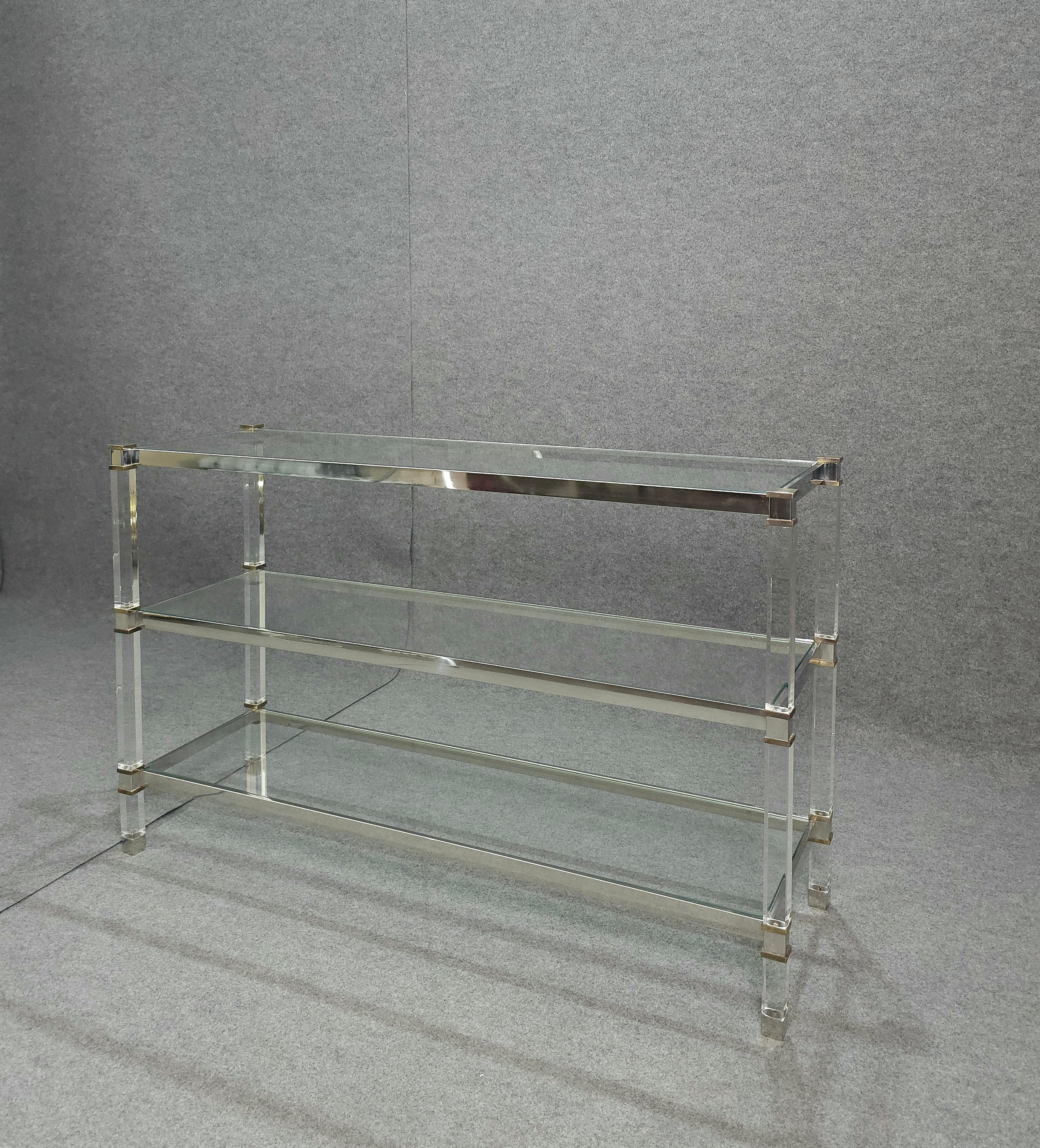 Plexiglass bookcase or wall unit with three shelves. Transparent glass shelves that rest on a chromed steel structure. Brass finishes. With its elegant line, it can also be used as a divider, suitable for any refined environment. Recommended