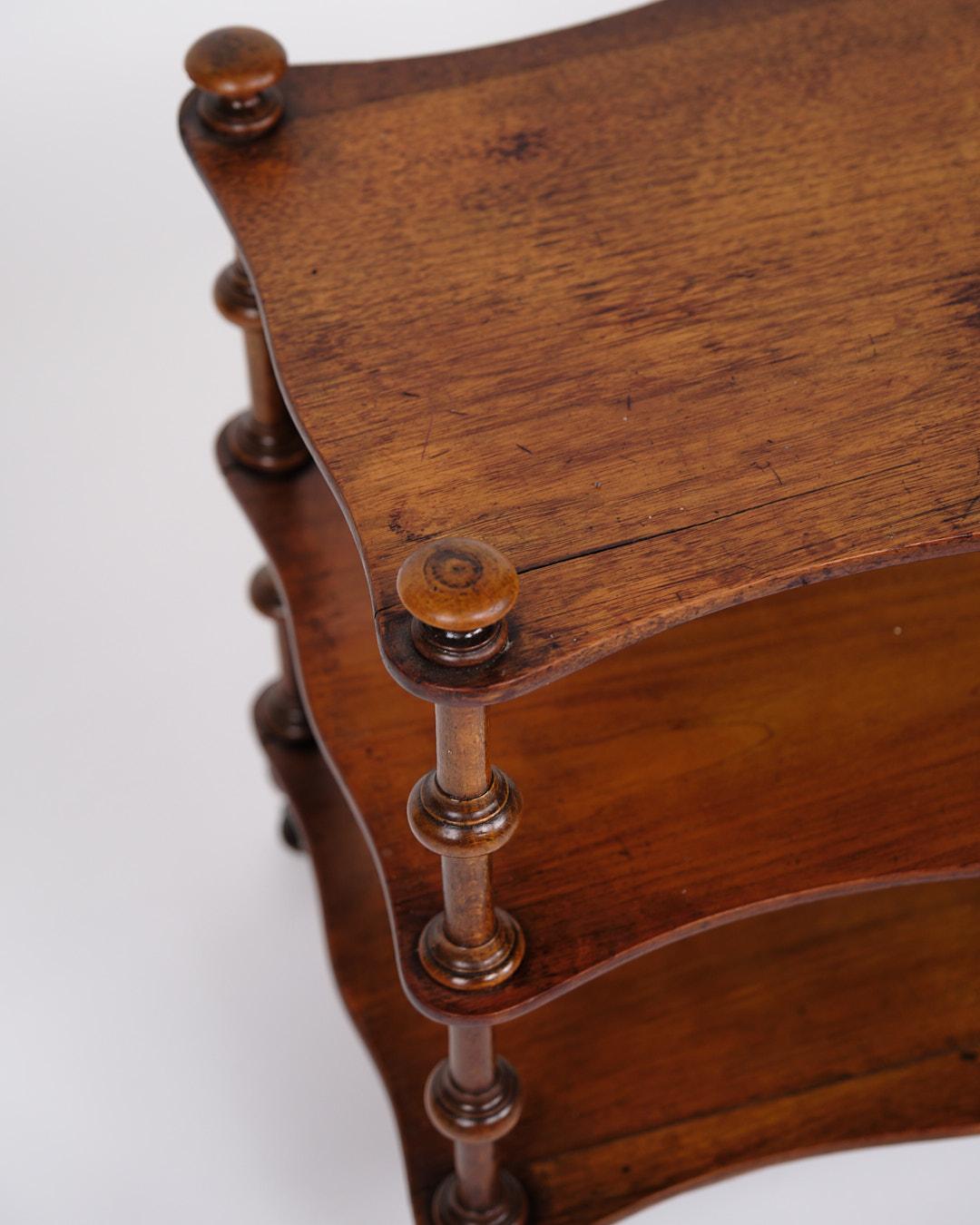 Libreria/scaffale in mogano del XIX secolo. Il mobile è arredato con tre mensole e colonne tornite dettagliate. Nella parte inferiore sono montate delle piccole ruote che garantiscono funzionalità e mobilità.

Un mobile d'epoca decorativo e utile