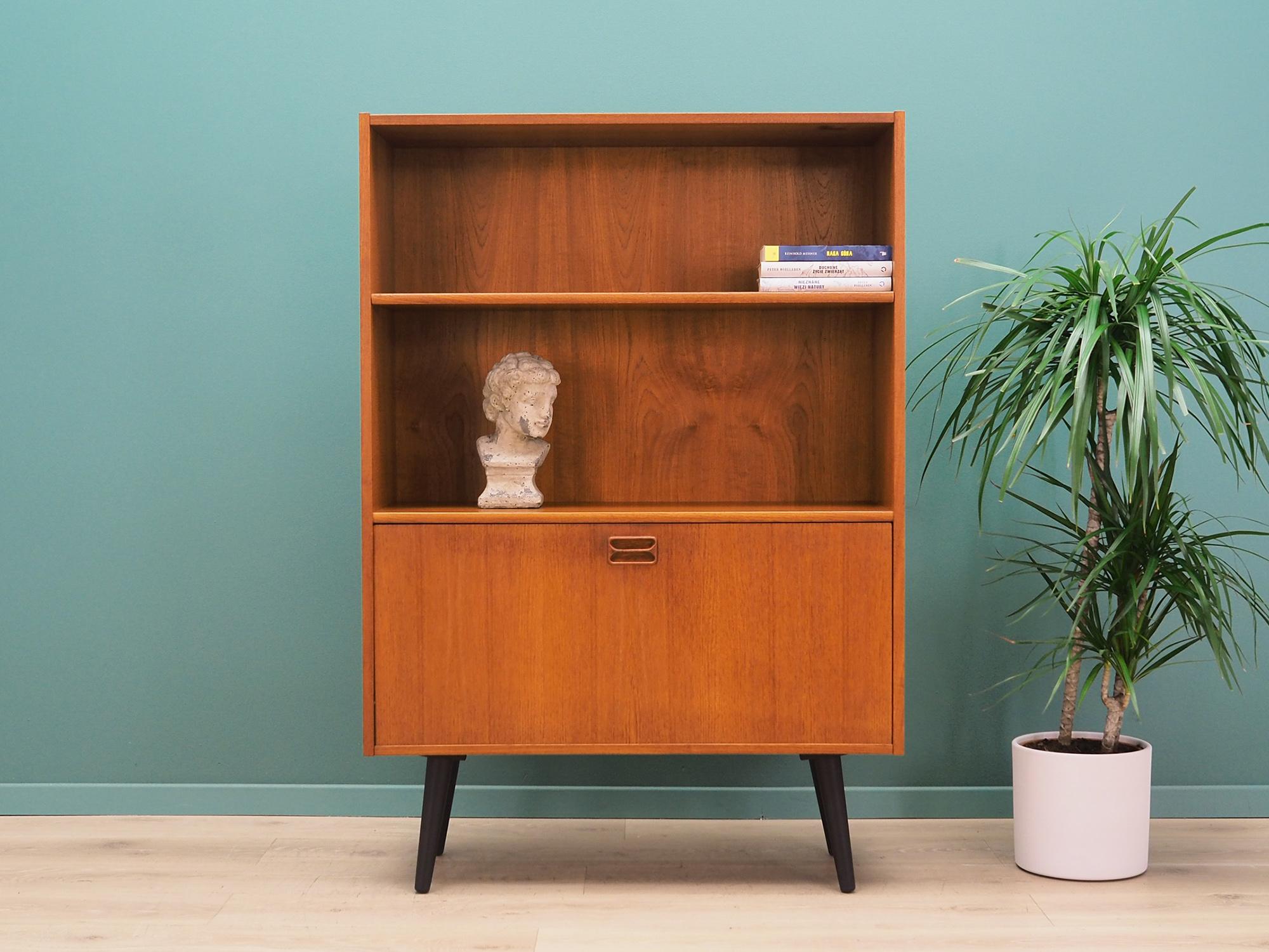 Bookcase was made in the 1960s, Danish production.

The structure is covered with teak veneer. Legs made of solid wood stained black. Surface after refreshing. Inside the space has been filled with practical shelves. Shelves are adjustable in