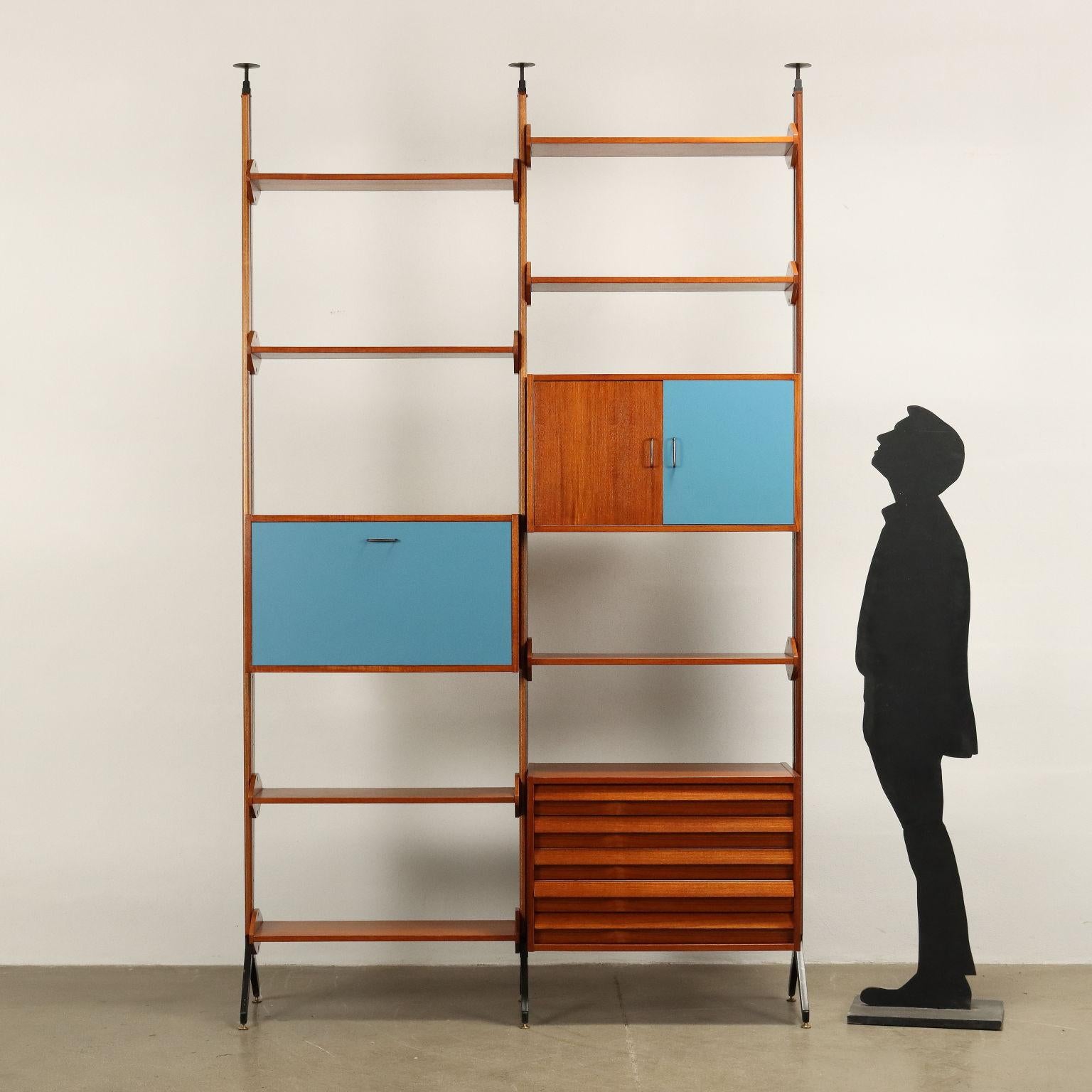 Bookcase also usable from the center, with extensible uprights for regular anchoring to the ceiling, shelf elements and containers with adjustable position. Solid wood and Teak veneer, Formica inserts, enamelled metal.