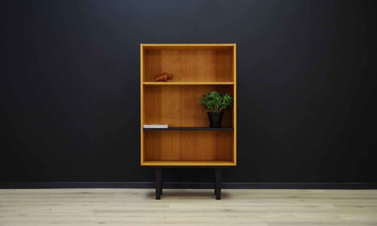 A classic bookcase with two adjustable shelves (the color of the bottom shelf-black). The bookcase comes from the turn of the 1960s-1970s, Scandinavian design, a Minimalist form veneered with ash. Preserved in good condition (visible bruises and