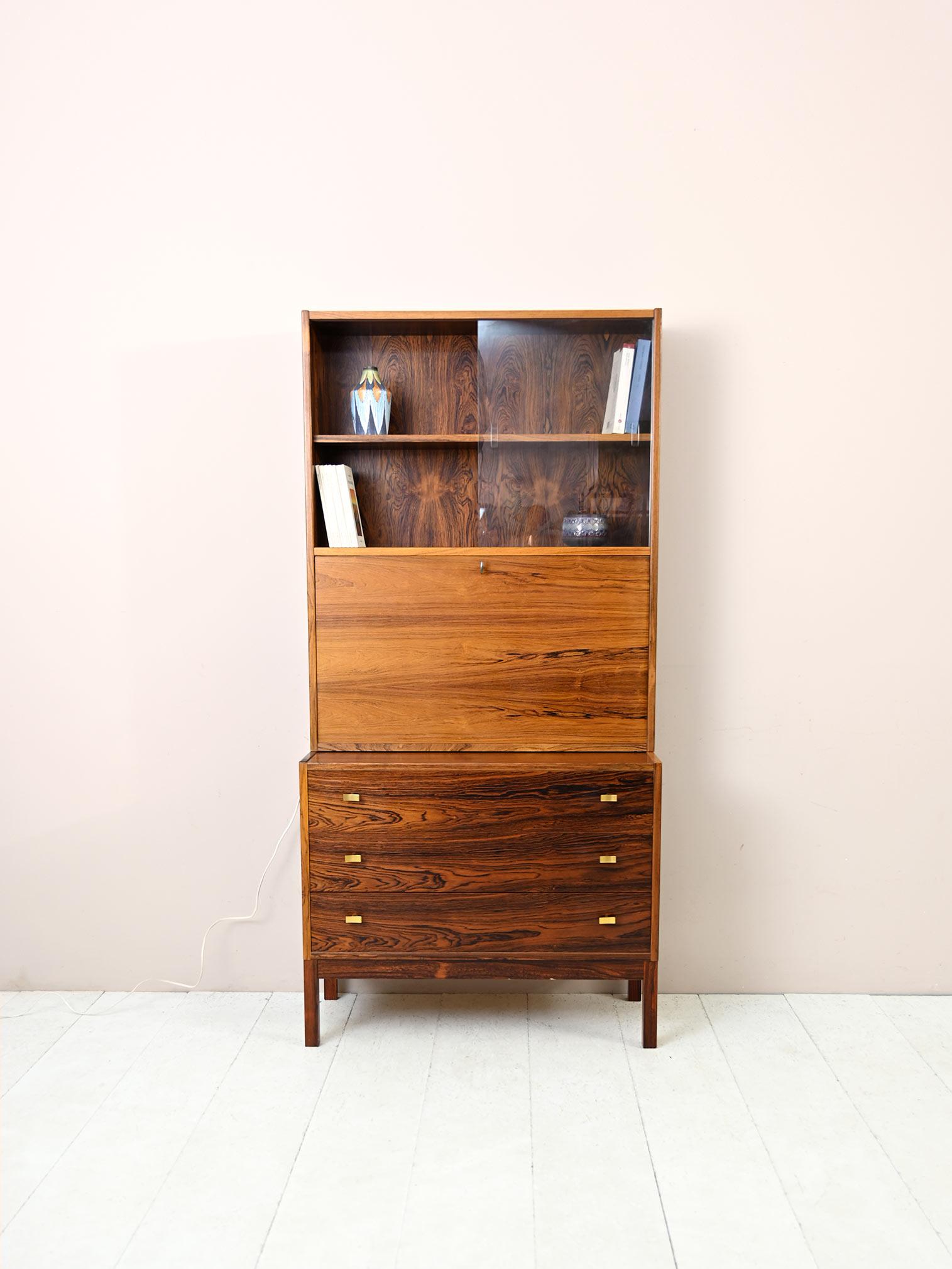 Vintage rosewood cabinet with gold detailing.

Elegant bookcase with drawers and flap of 1960s Scandinavian manufacture.
Consisting of two modules it can be easily moved and assembled. The lower part is a chest of drawers with three drawers with