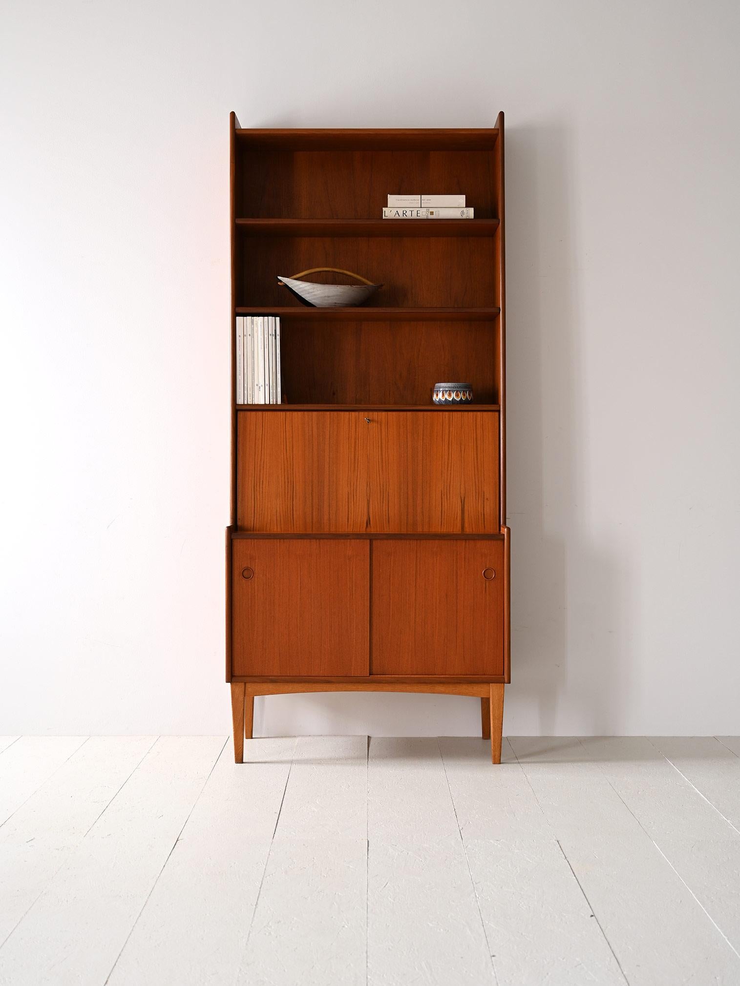 1960s teak cabinet with flap and shelves.

Particular piece of vintage furniture consisting of a frame whose lower part has a storage compartment with sliding doors while the upper part has two shelves and a compartment with a flap.
A functional
