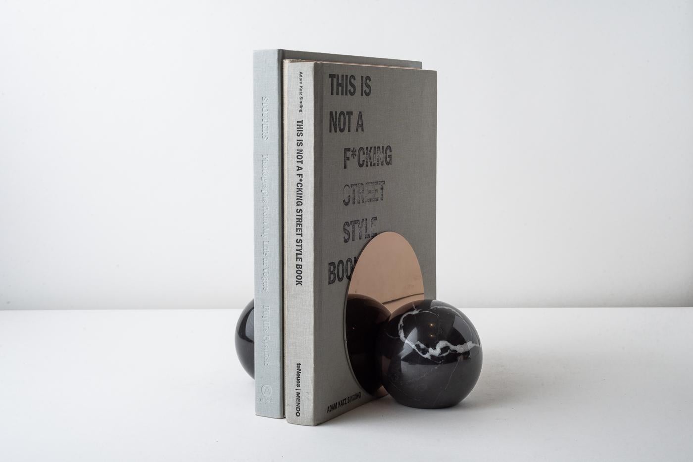 Introducing a truly luxurious addition to your personal library - a stunning pair of hand-carved marble bookends from the artisanal experts at bruci. These spherical bookends are exquisitely detailed with a vertical stainless steel plate boasting a
