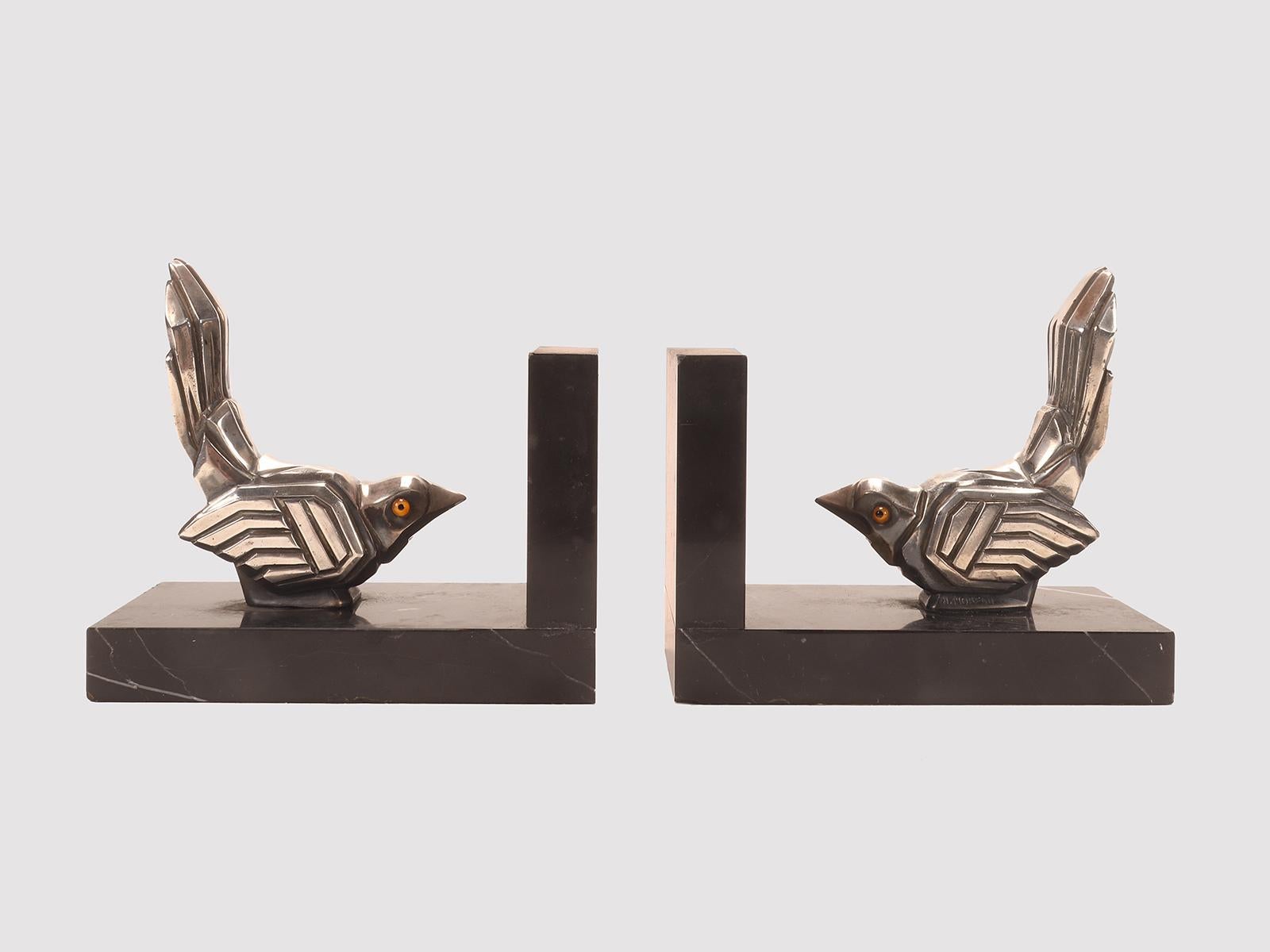 Pair of Art Deco bookends in black marble with orthogonal L-shaped structure. On the marble base there are two identical metal sculptures, depicting two sparrow birds with glass paste eyes. Signed H. Moreau. France circa 1925.
