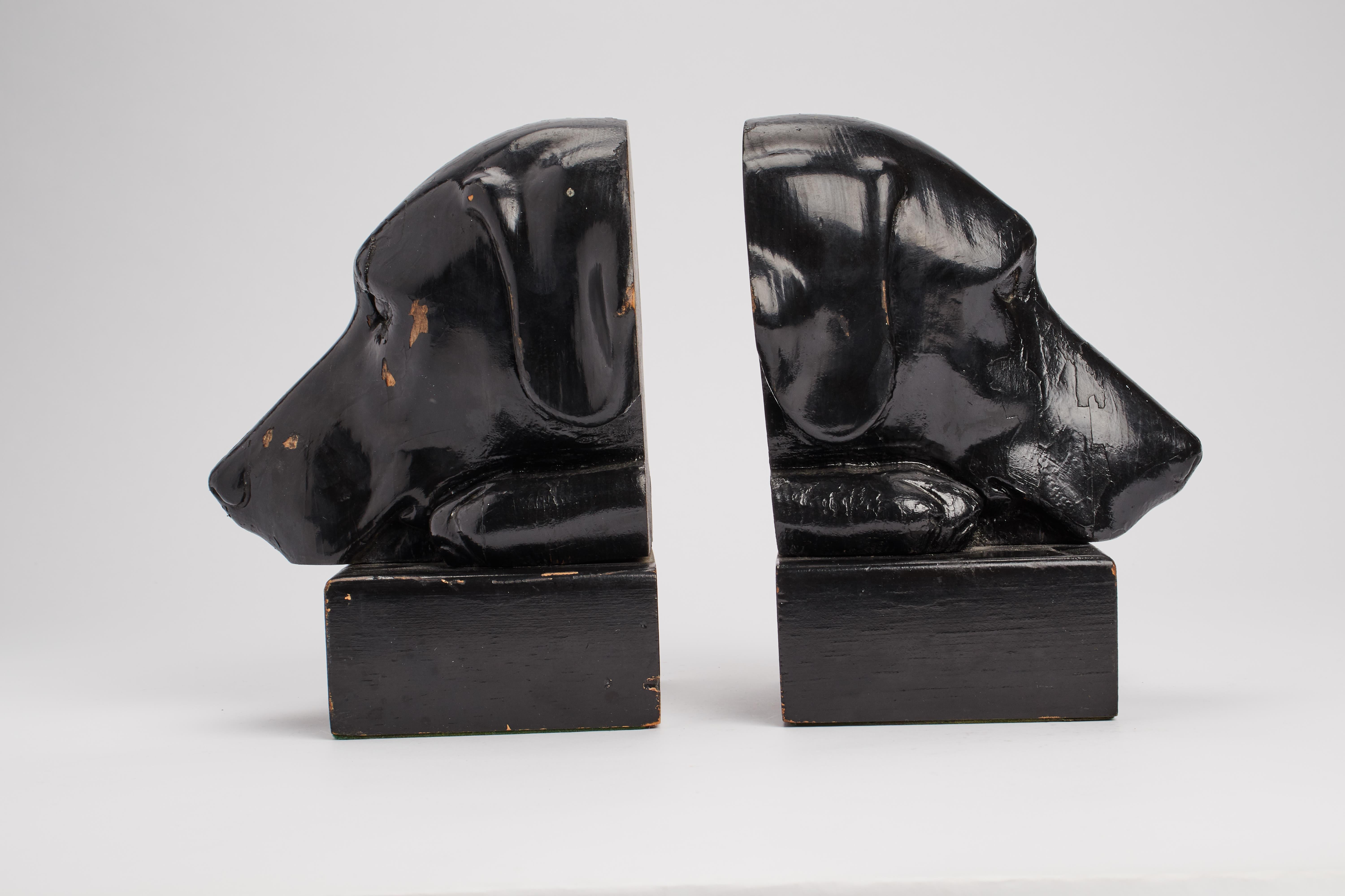 Large pair of carved and lacquered black wooden bookends, depicting two black Labrador dog heads. England, late 19th century.
