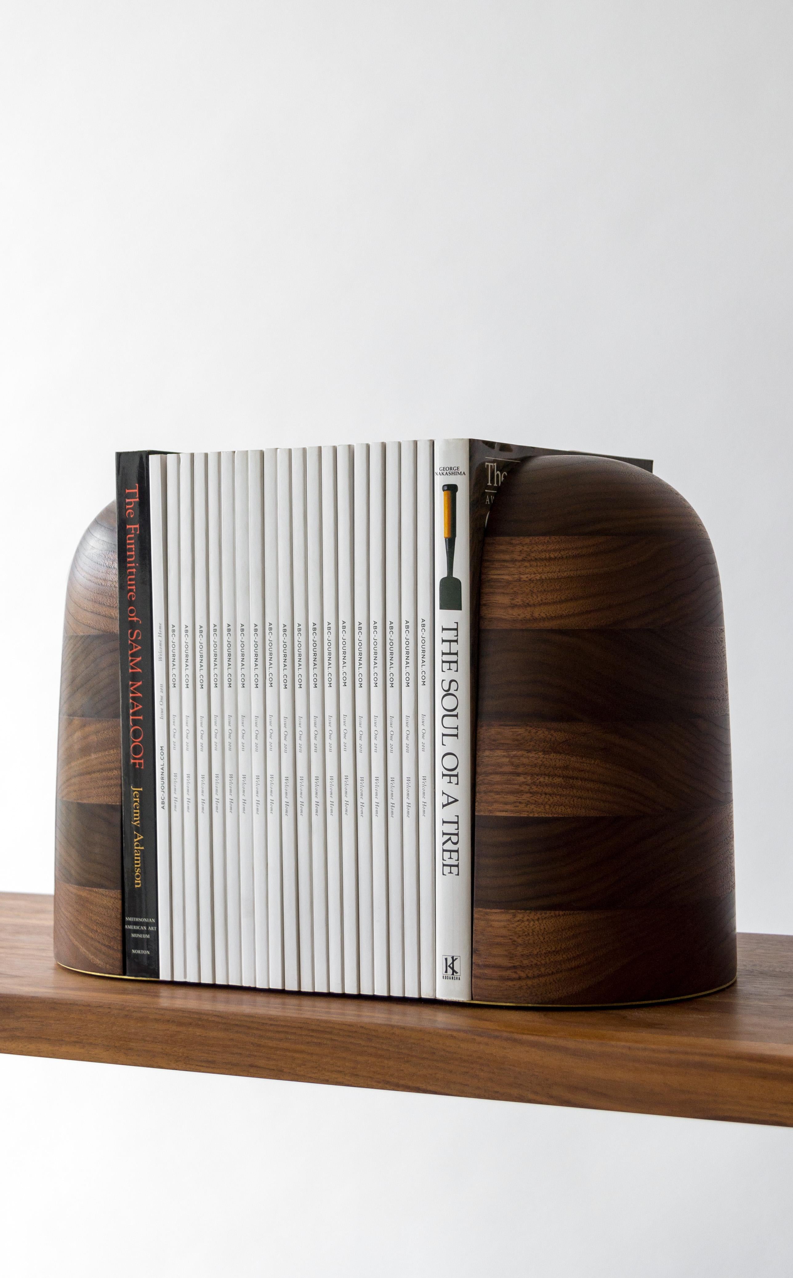 Hand-turned bookstops in selectively ebonized walnut with brass detailing. These beautiful and functional book ends come in a hand rubbed oil finish and are also available in maple and blackened steel. Bookends are sized to fit paperbacks to coffee