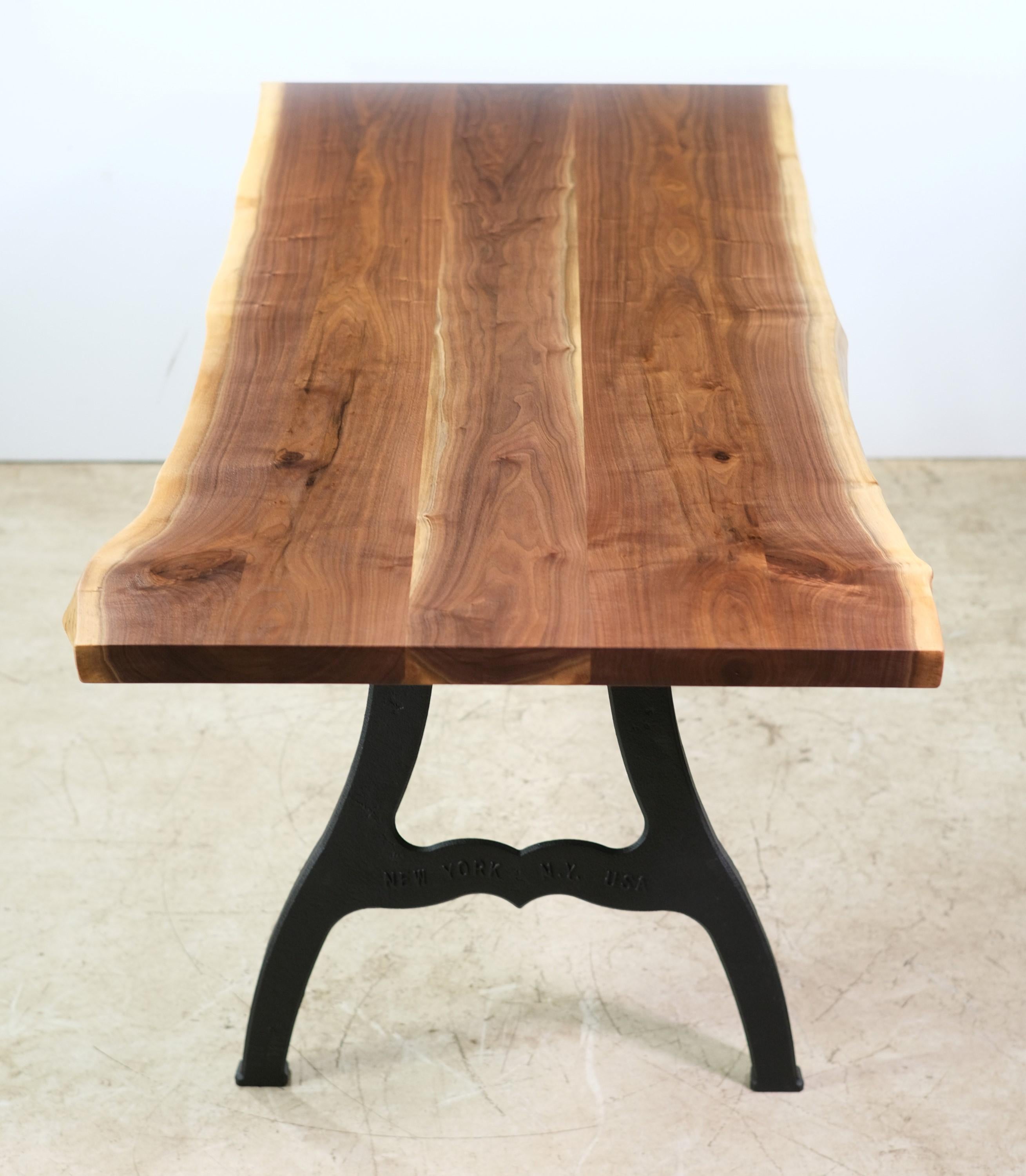 Solid live edge walnut table. Three plank top with the two outside planks bookmatched. Paired with embossed New York, NY industrial cast iron legs. Please note, this item is located in one of our NYC locations.