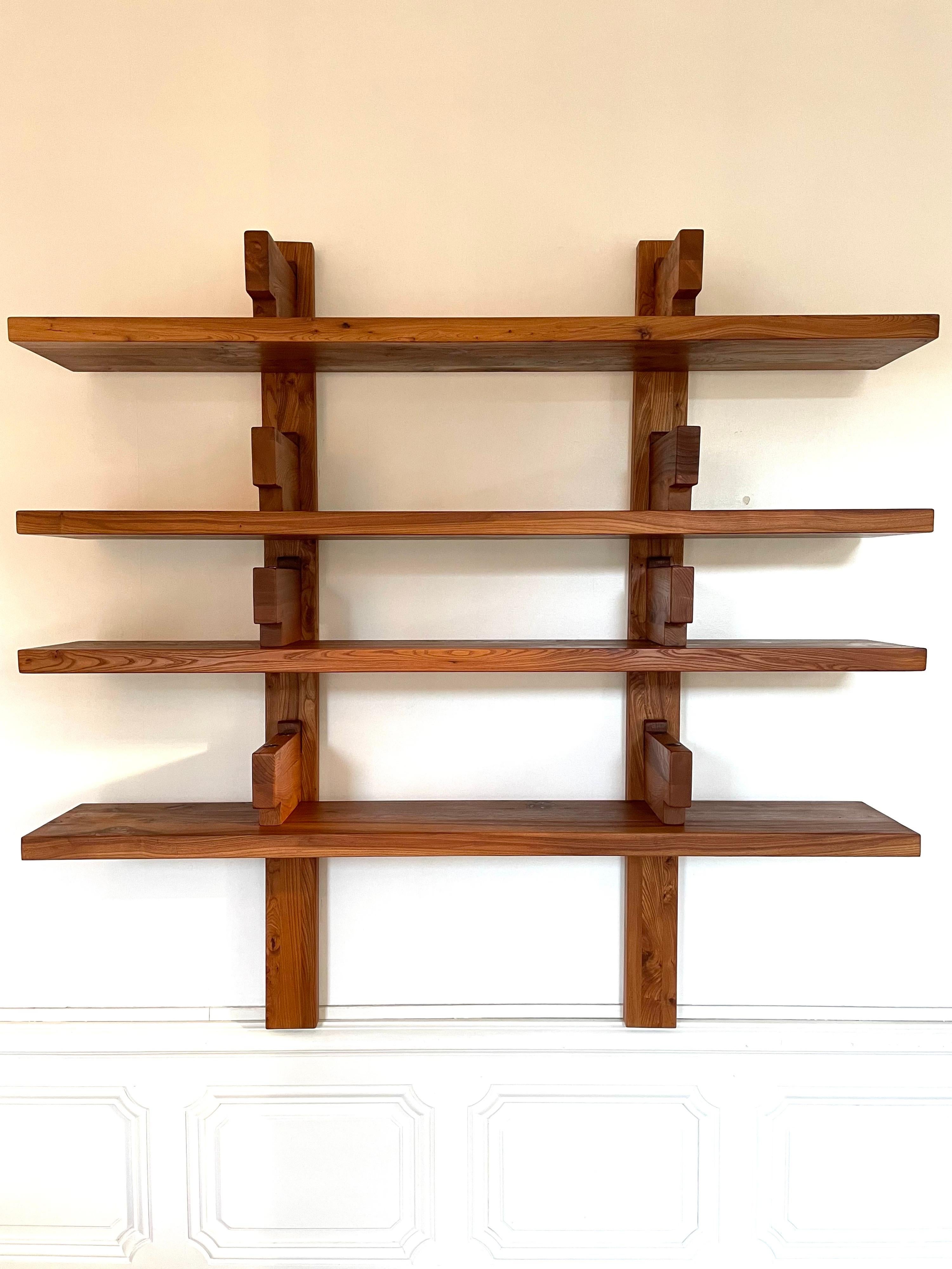 Bookshelf B17 A by Pierre Chapo from 1970 in French Elm 1st edition.

Four shelves, fixed below eight consoles which wedge the books by Brass headed screws, the two vertical uprights carry on the floor their fixing to the wall does not support the