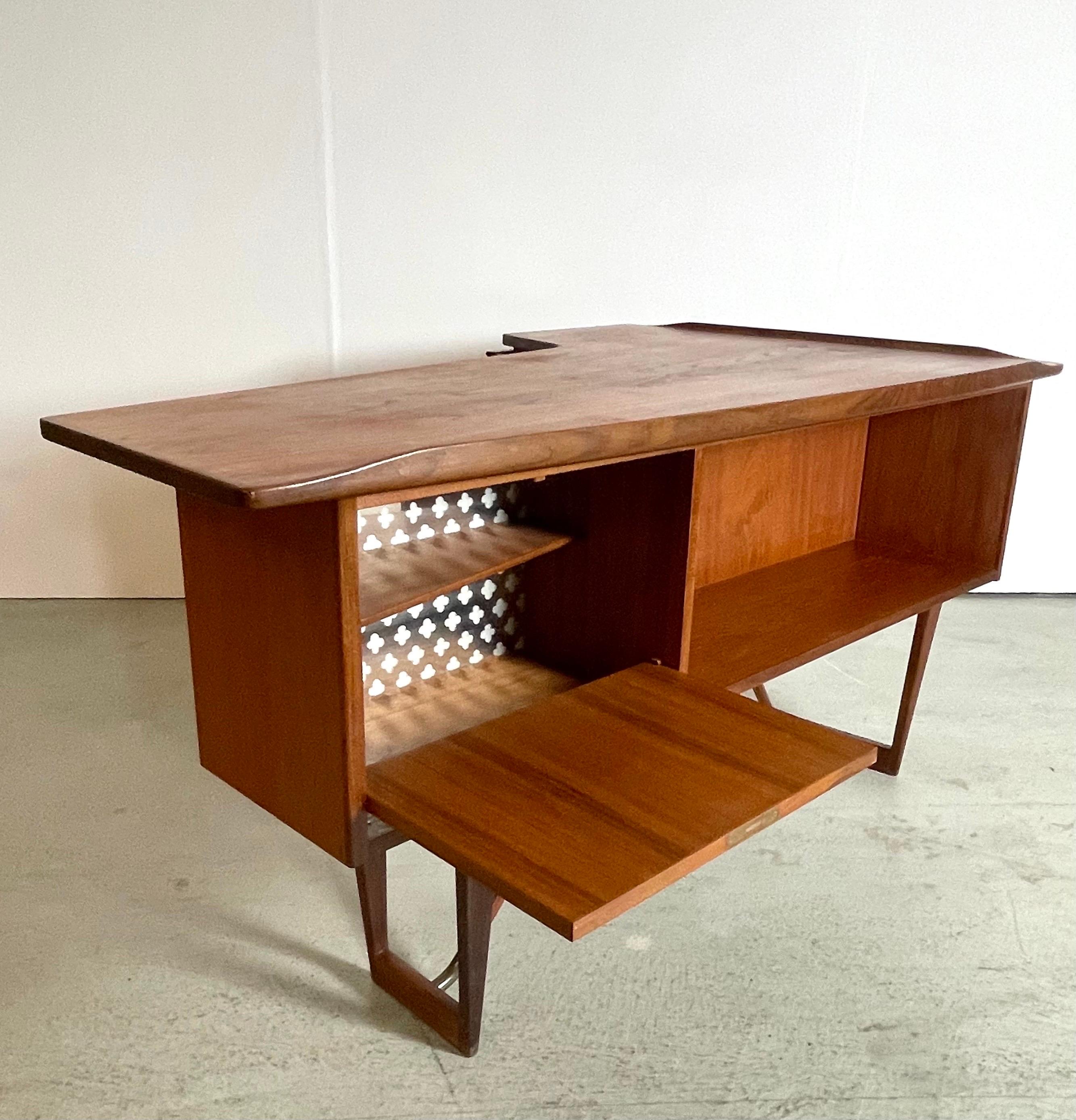 A very special desk designed by Peter Løvig Nielsen. Made in Denmark, produced by Hedensted Møbelfabrik. It features a boomerang shaped table top with raised edges, three drawers in the front side and a cabinet and open space in the backside. It can