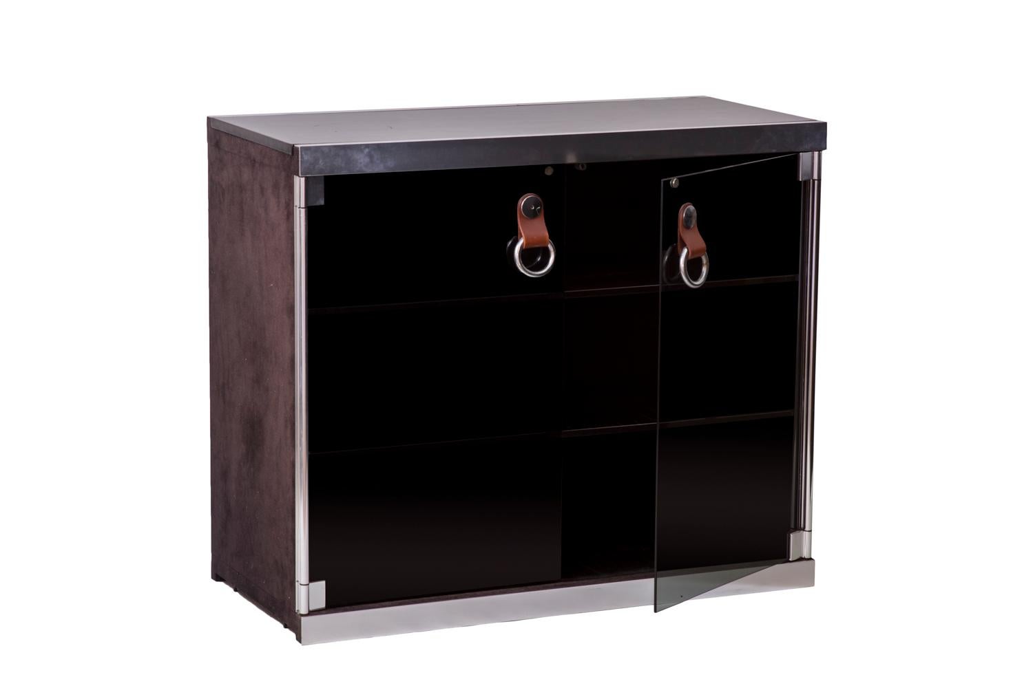 Guido Faleschini for Hermès, attributed to.
Modular cabinet opening by two smoked glass door leaves thanks to brown leather handles, on two compartments in black lacquered wood with two shelves in each one.
Structure and mounts in chromed metal.