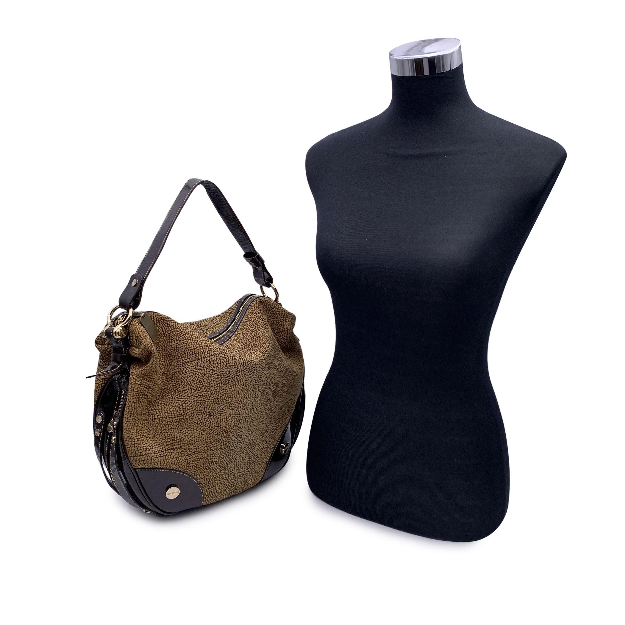 Beautiful Borbonese tote hobobag in brown Op suede with brown patent leather trim and shoulder strap. Zip detailing around the bag. Gold metal hardware. Upper zipper closure. Brown fabric lining. 1 side zip pocket inside. 1 side zip pocket inside.