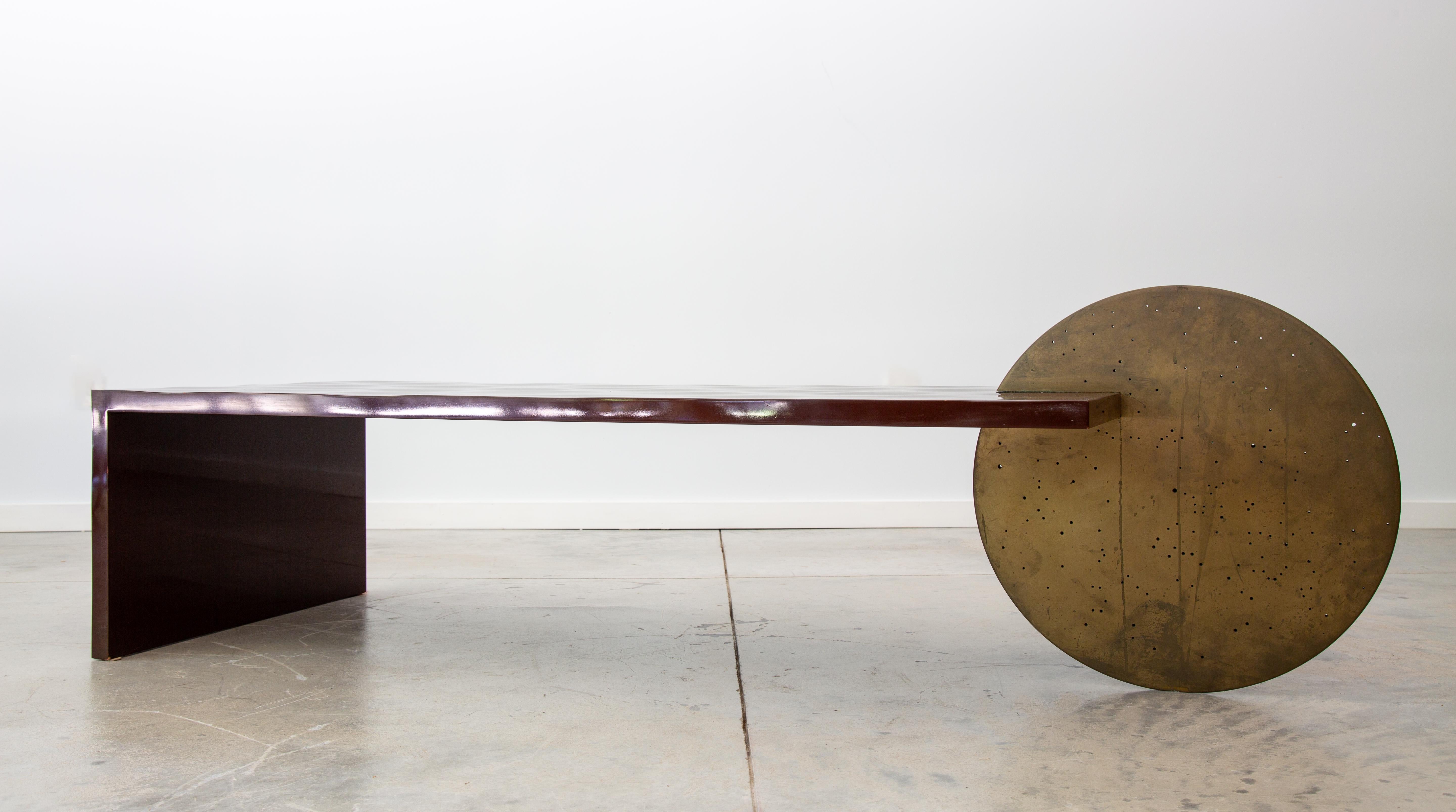 A Borealis table by famed designer Patrick Elie Naggar, consisting of a sculpted hardwood surface and a brass coated polymer disc.  This table is an early example, which Patrick estimated to be from 2003, and comprises a maroon red high gloss