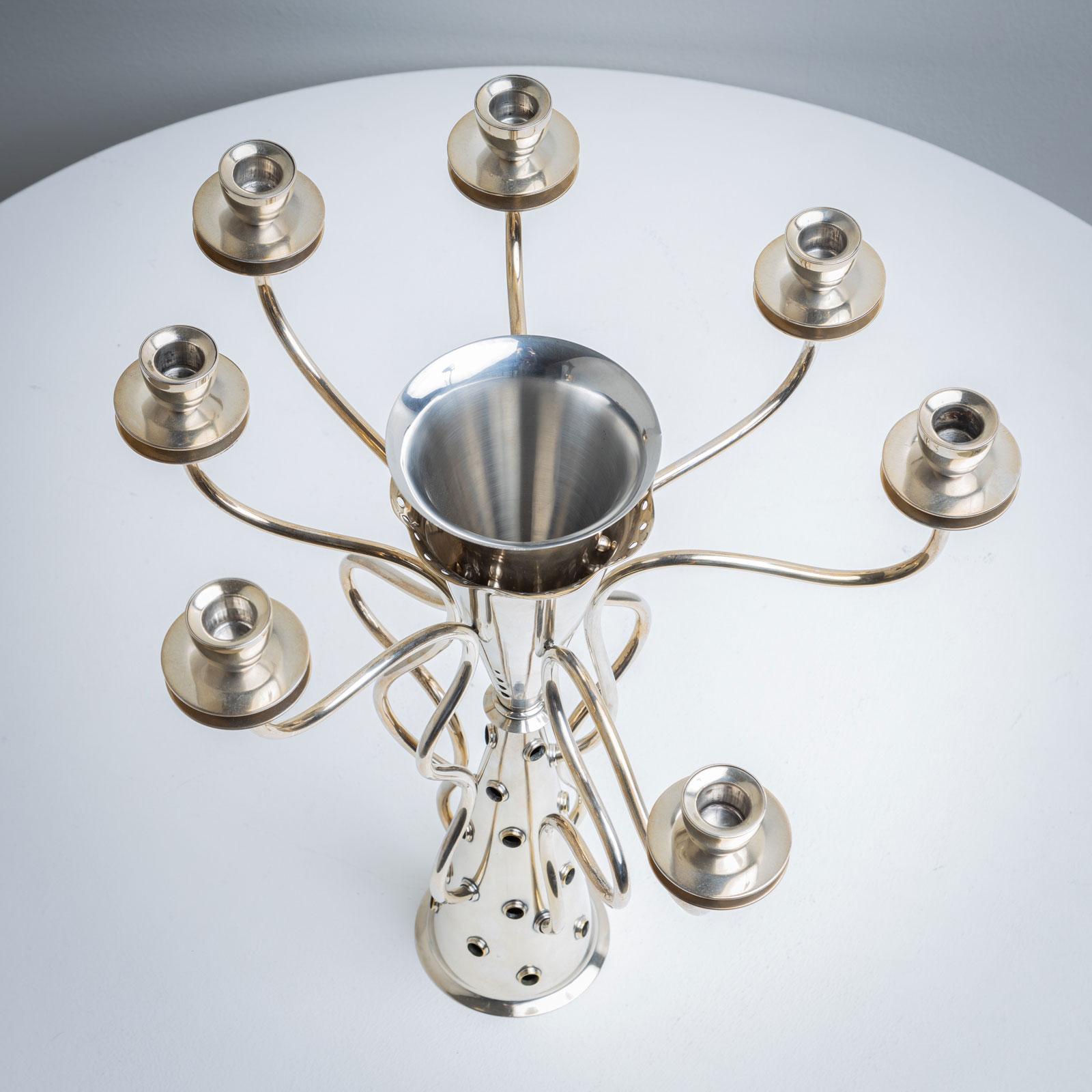 Seven-armed candle holder made of silver-plated metal with company stamp “Driade” on the underside. The conical body is surrounded by seven winding arms, each with a spout, in an irregular rhythm. It was made by Fossadello di Caorso, Piacenza,
