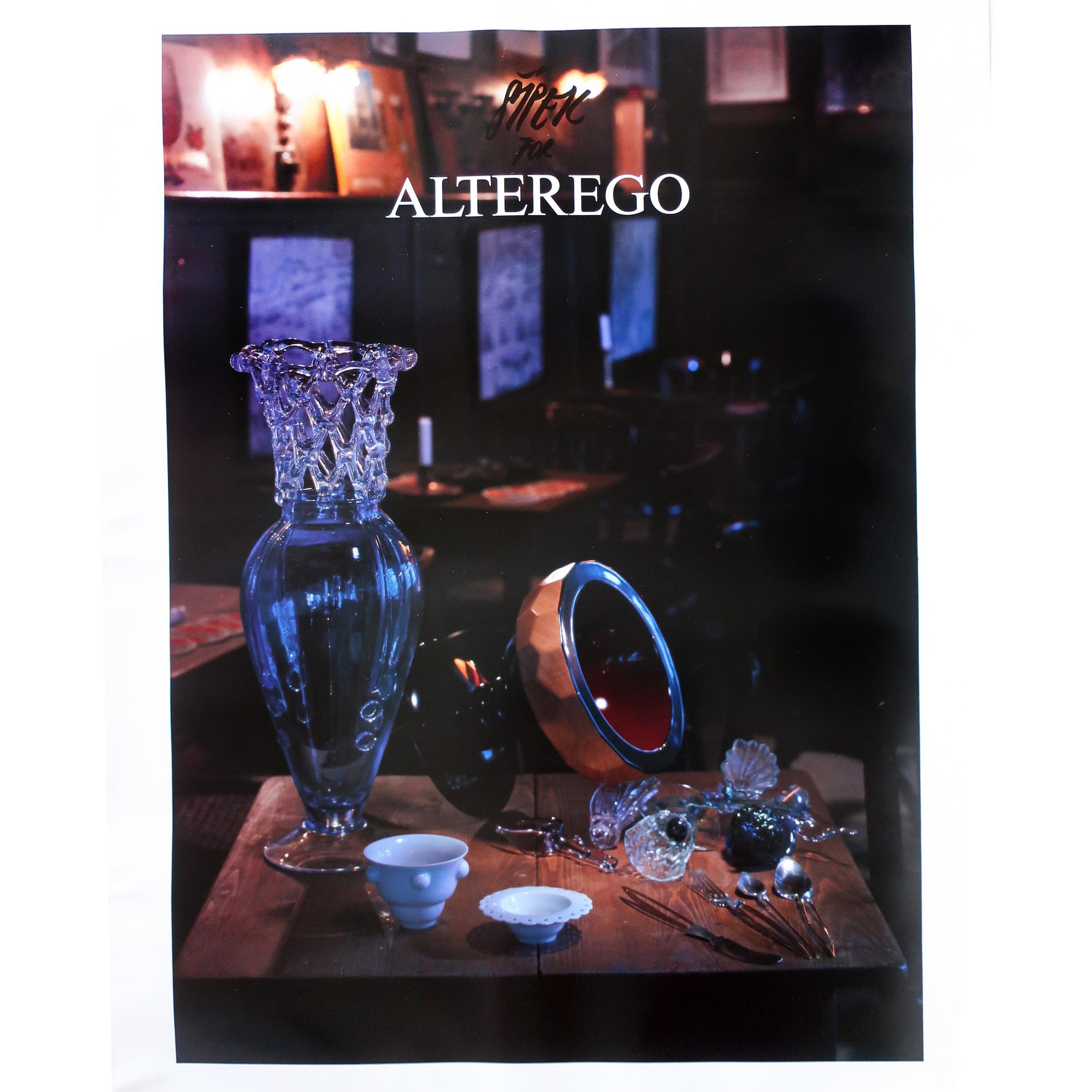 A promotional poster for Czech architect and designer Borek Sipek's work with his design studio Alterego producing works in glass in the 1980s and 1990s. Features a number of Sipek designed pieces on a wood table.
