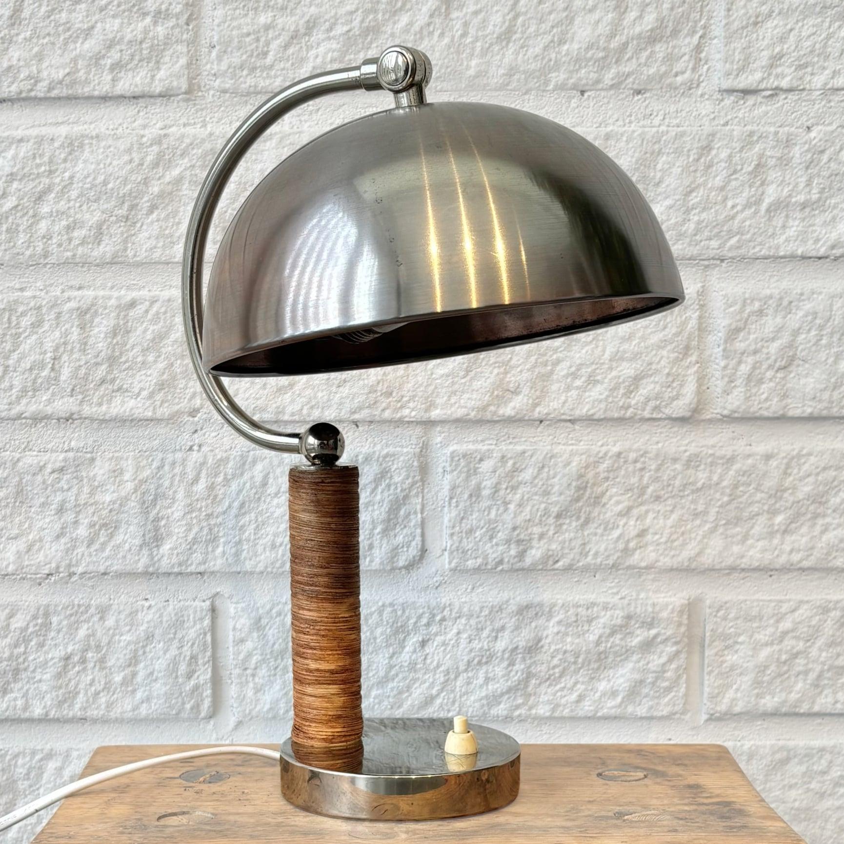 Lampe de bureau moderniste scandinave produite par le fabricant suédois Boréns dans les années 1930. Construit avec un pied circulaire en acier chromé supportant un pilier cylindrique enveloppé de rotin et un bras en acier incurvé avec une sphère